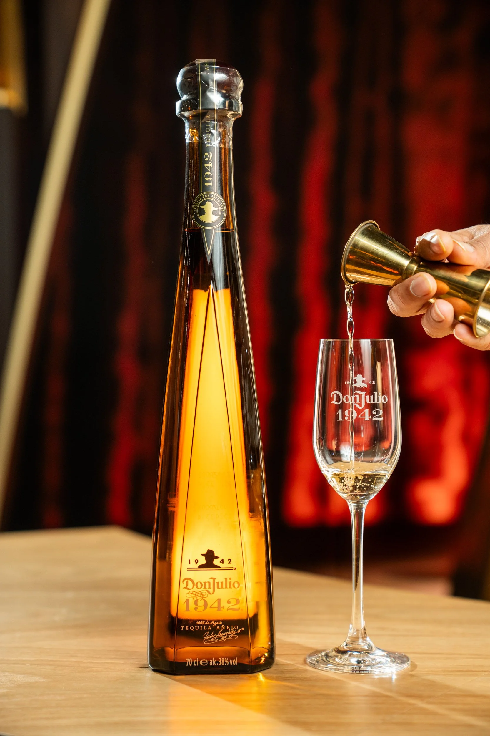 A bottle of Don Julio 1942 tequila and a glass being poured with tequila.