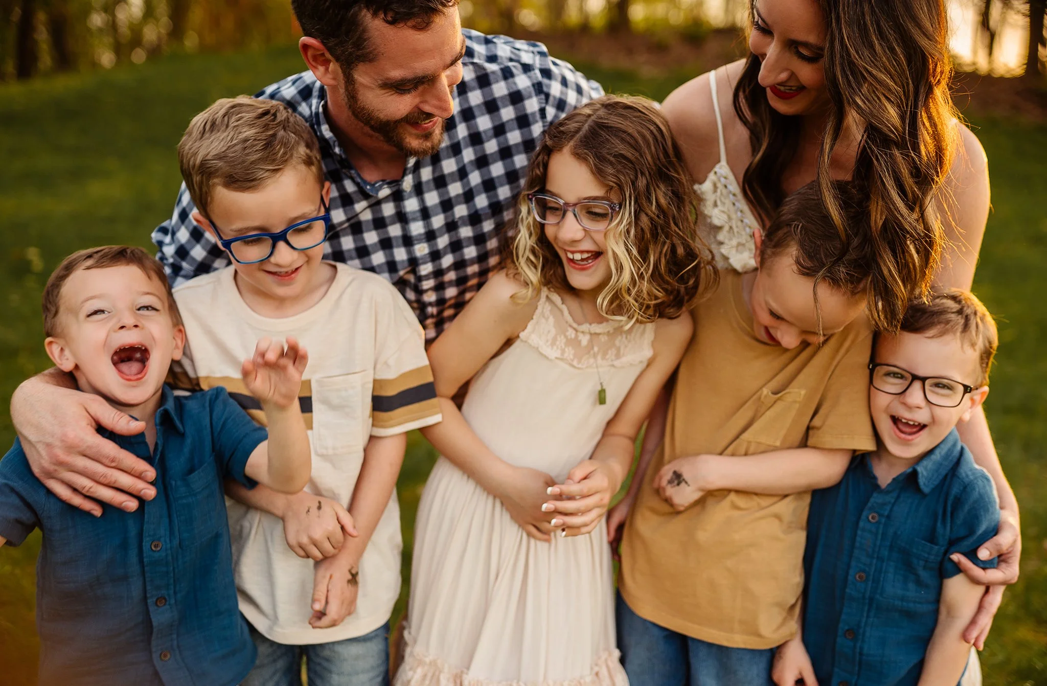 A group of seven people, including children and adults, smiling and enjoying themselves outdoors in a park during sunset. Family sessions canal fulton, ohio golden hour