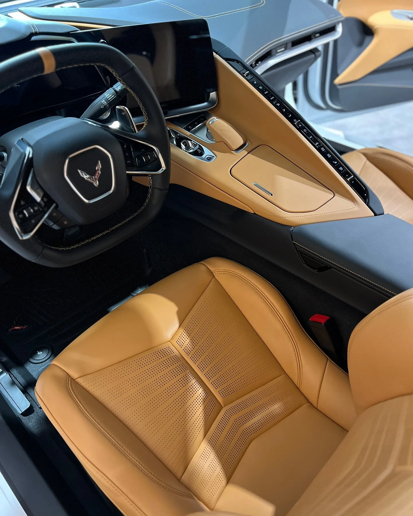 Interior of a modern Corvette with tan leather seats, black and tan dashboard, and a digital display.