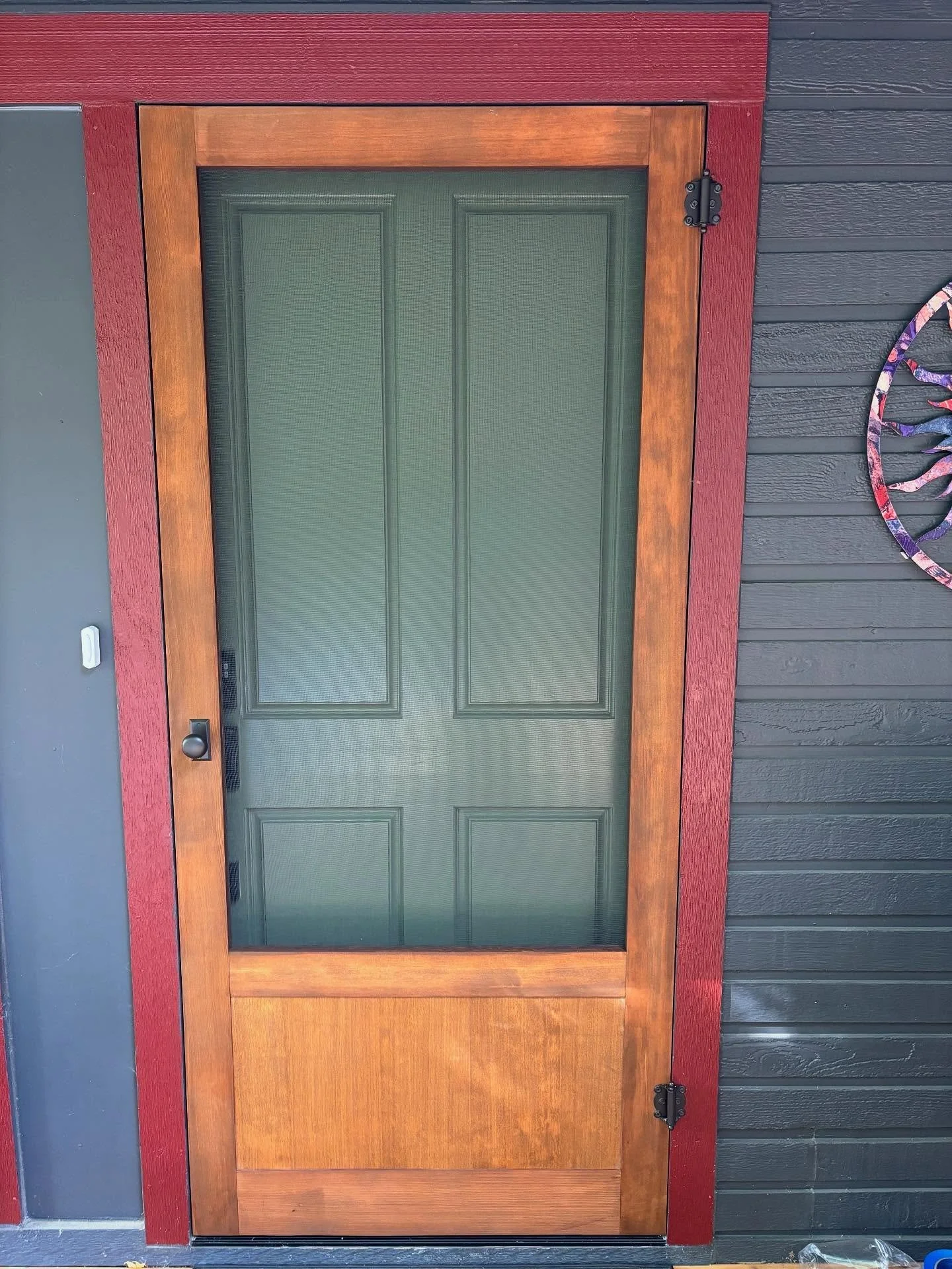 This screen door features a solid panel at the bottom and a clean, precise fit. The home overlooks tall trees and has a beautiful open entrance. With the door open, you get a stunning view straight through the screen door, out the back windows, and i