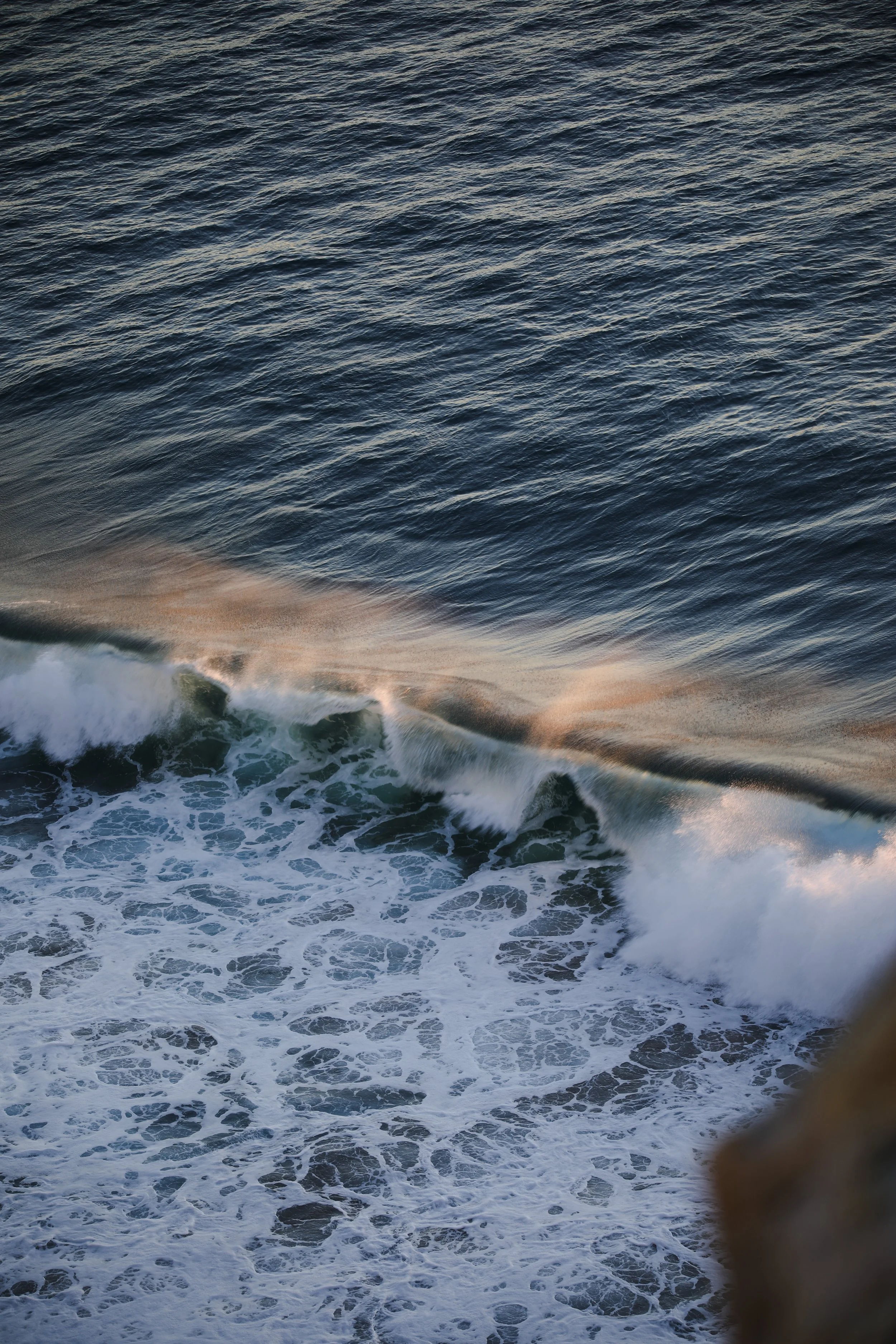 Ocean waves crashing against the shore during sunset.