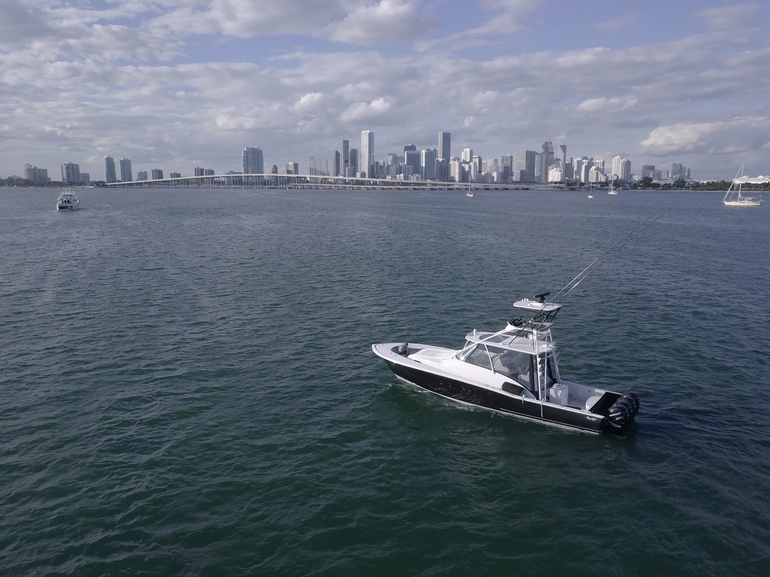 A white and black motorboat on calm water with a city skyline in the background