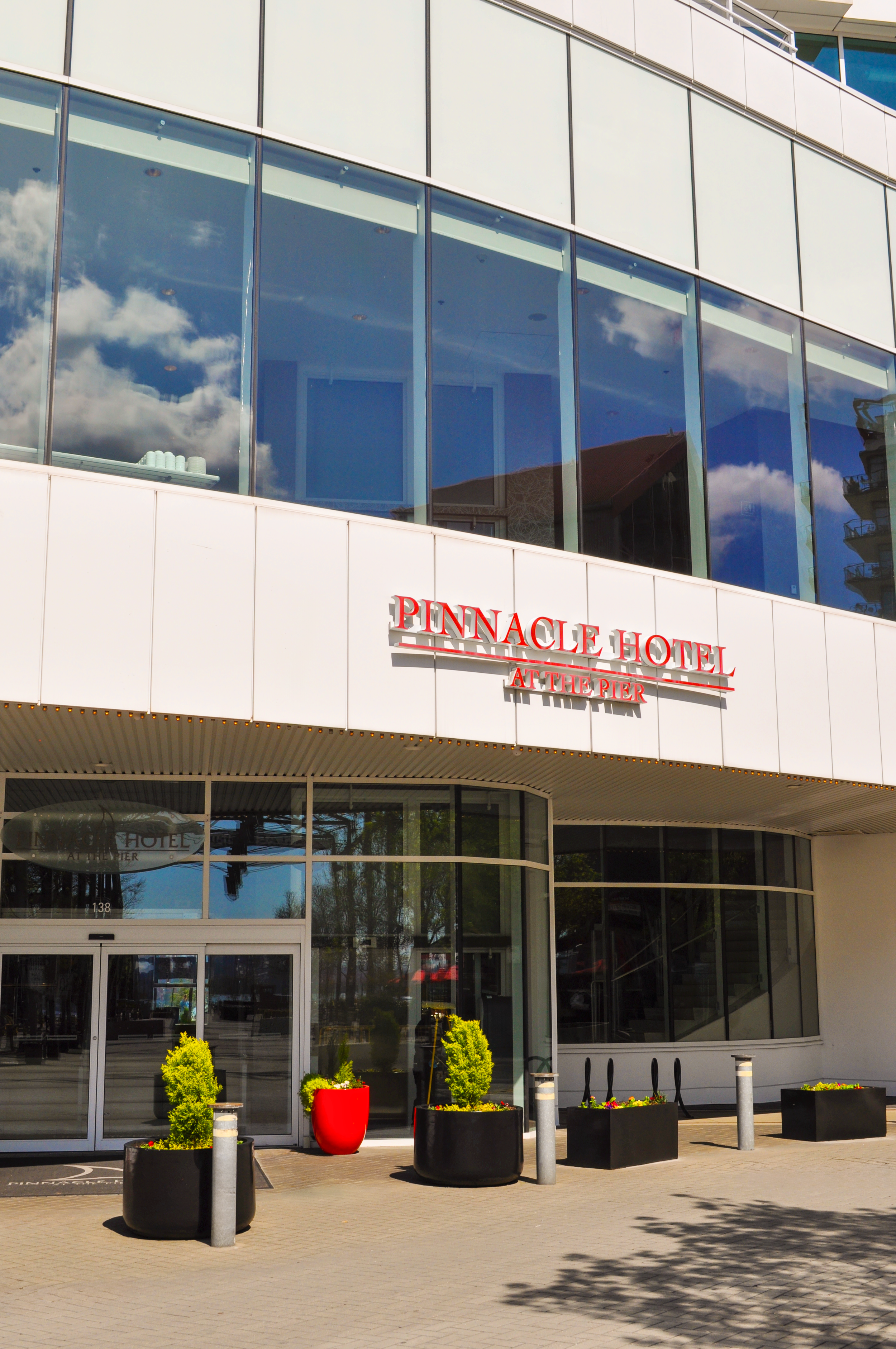 Exterior entrance of the Pinnacle Hotel at the Pier with glass windows, red signage, and planters.