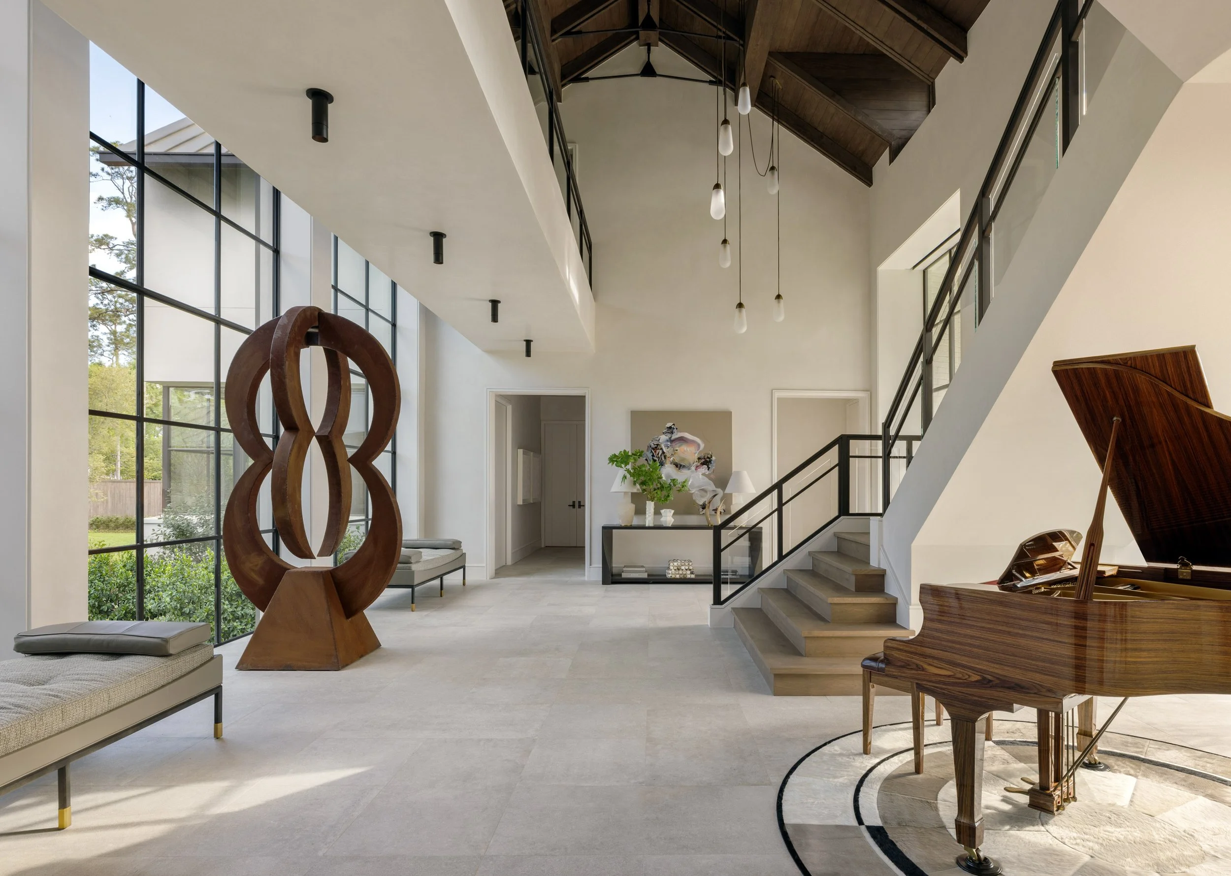 Benjamin Johnston Design Houston interior architecture and interior design featuring soaring vaulted ceiling with exposed wood beams, floor-to-ceiling steel windows, large scale sculptural artwork, and grand piano.