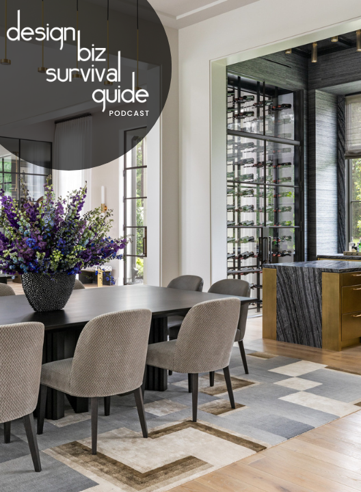 Modern dining room with a black table, beige chairs, a large floral arrangement, and a wine cellar visible through a glass wall.