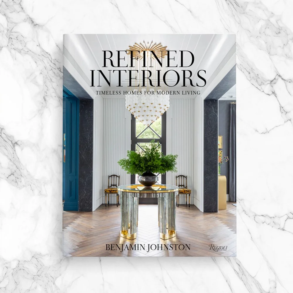 Book cover titled "Refined Interiors" by Benjamin Johnston, featuring a modern interior with a table, green foliage, and elegant decor.