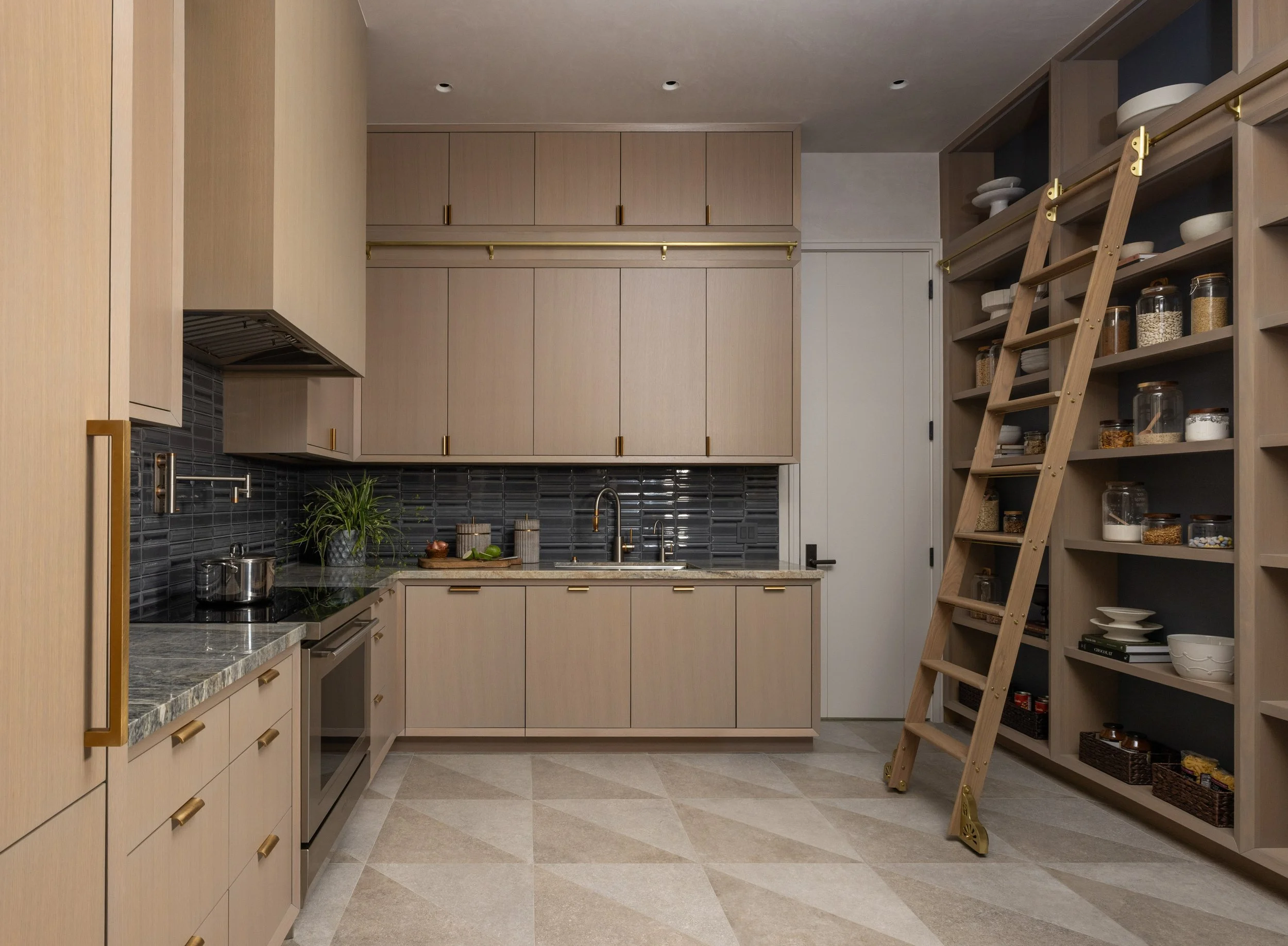 A modern kitchen with light wood cabinets, black tile backsplash, a granite countertop, open shelving with jars of food, and a wooden ladder for reaching high shelves.