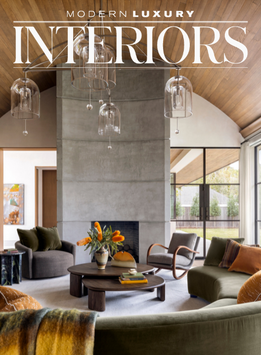 Modern living room with a fireplace, wooden ceiling, glass pendant lights, and large windows showing an outdoor patio.