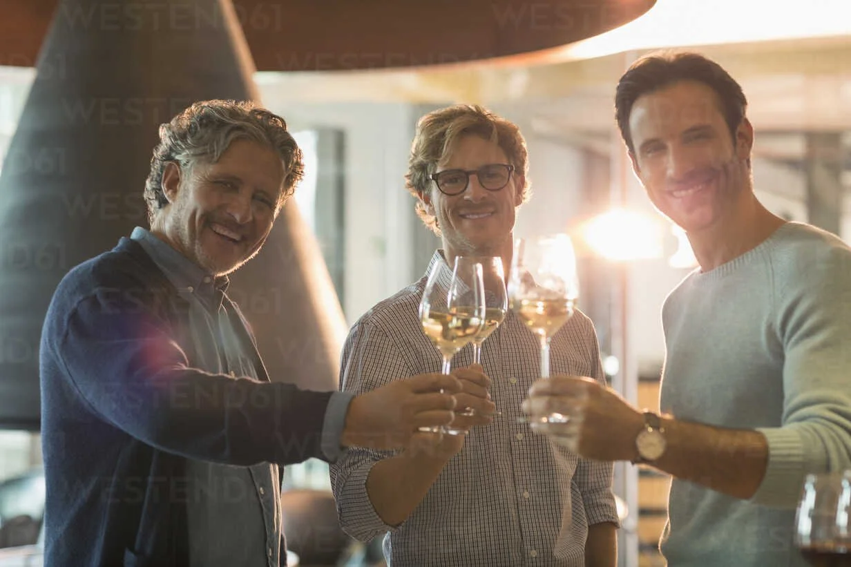 portrait-smiling-men-drinking-white-wine-at-winery-CAIF13625.jpeg