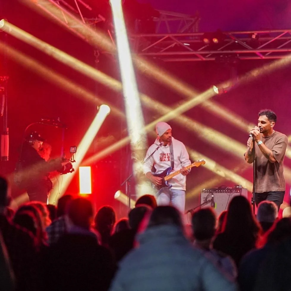 Marlon x Rulla singing on stage at a concert with red lights. Treaty Day Out: an electrifying performance.