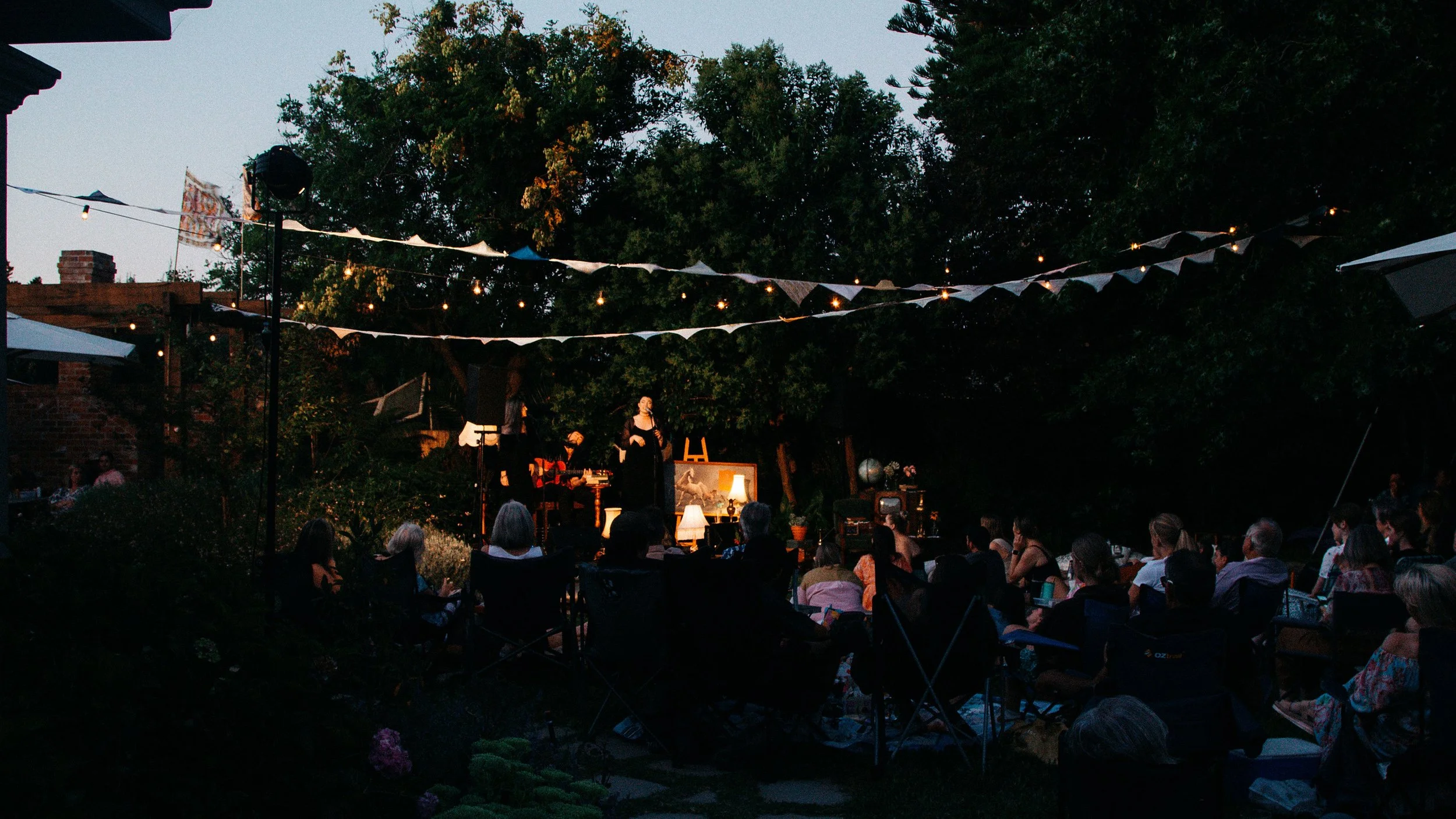 People leisurely seated in lawn chairs, immersed in the delightful atmosphere of the 'Secret Garden Gig'.