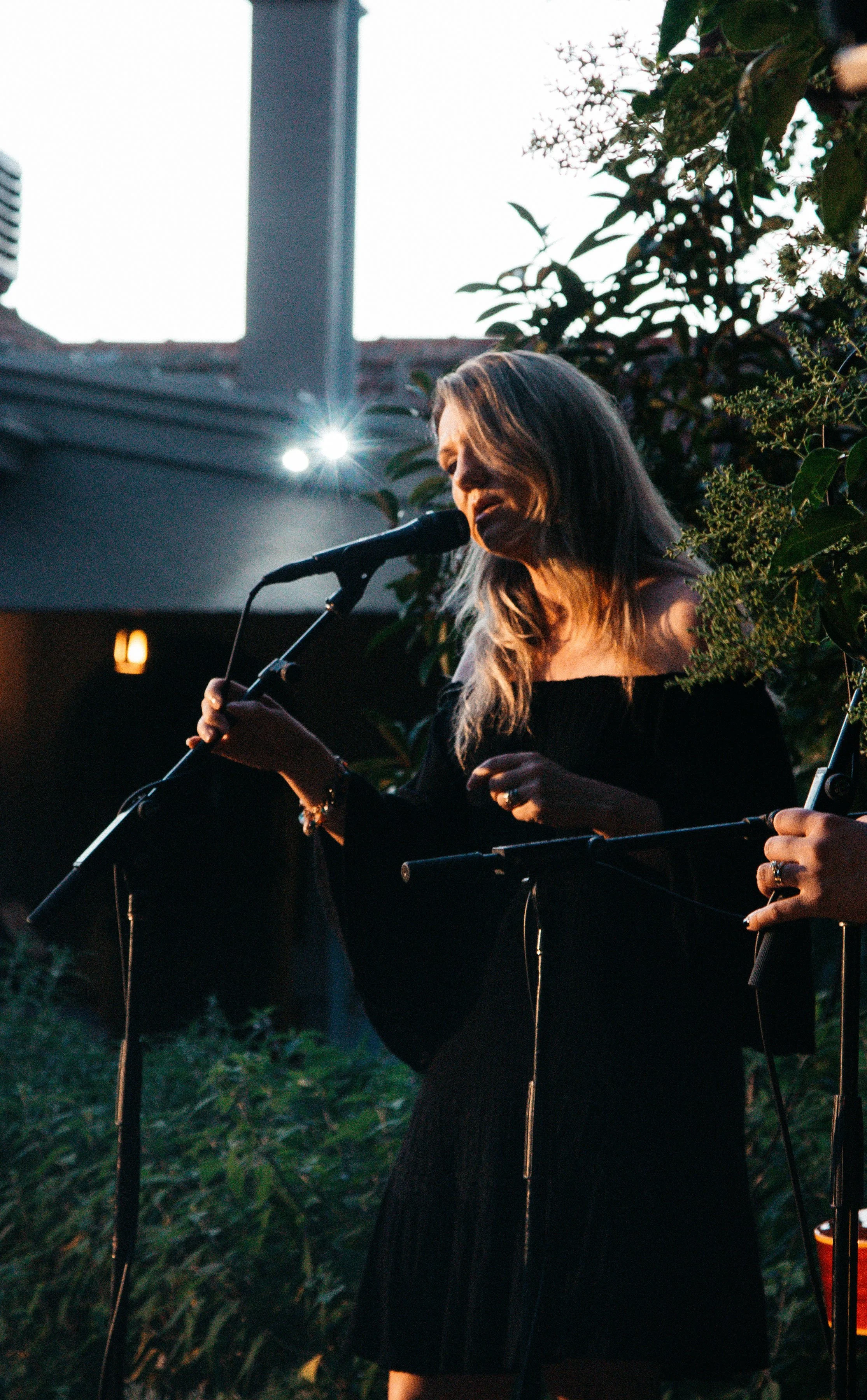 A woman passionately singing into a microphone as a man skillfully plays the guitar.