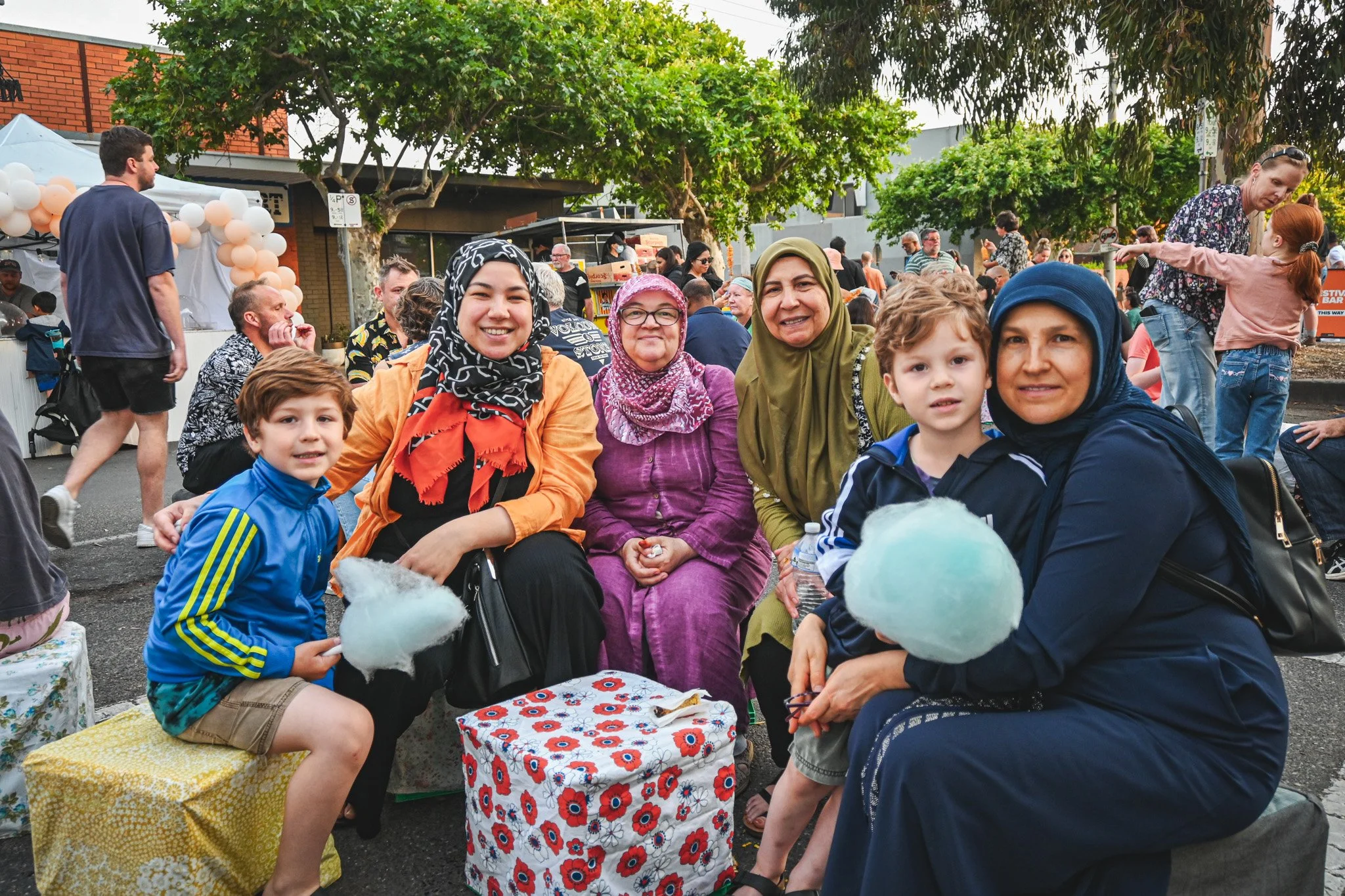 A group of people enjoying cotton candy at a food festival on a street.