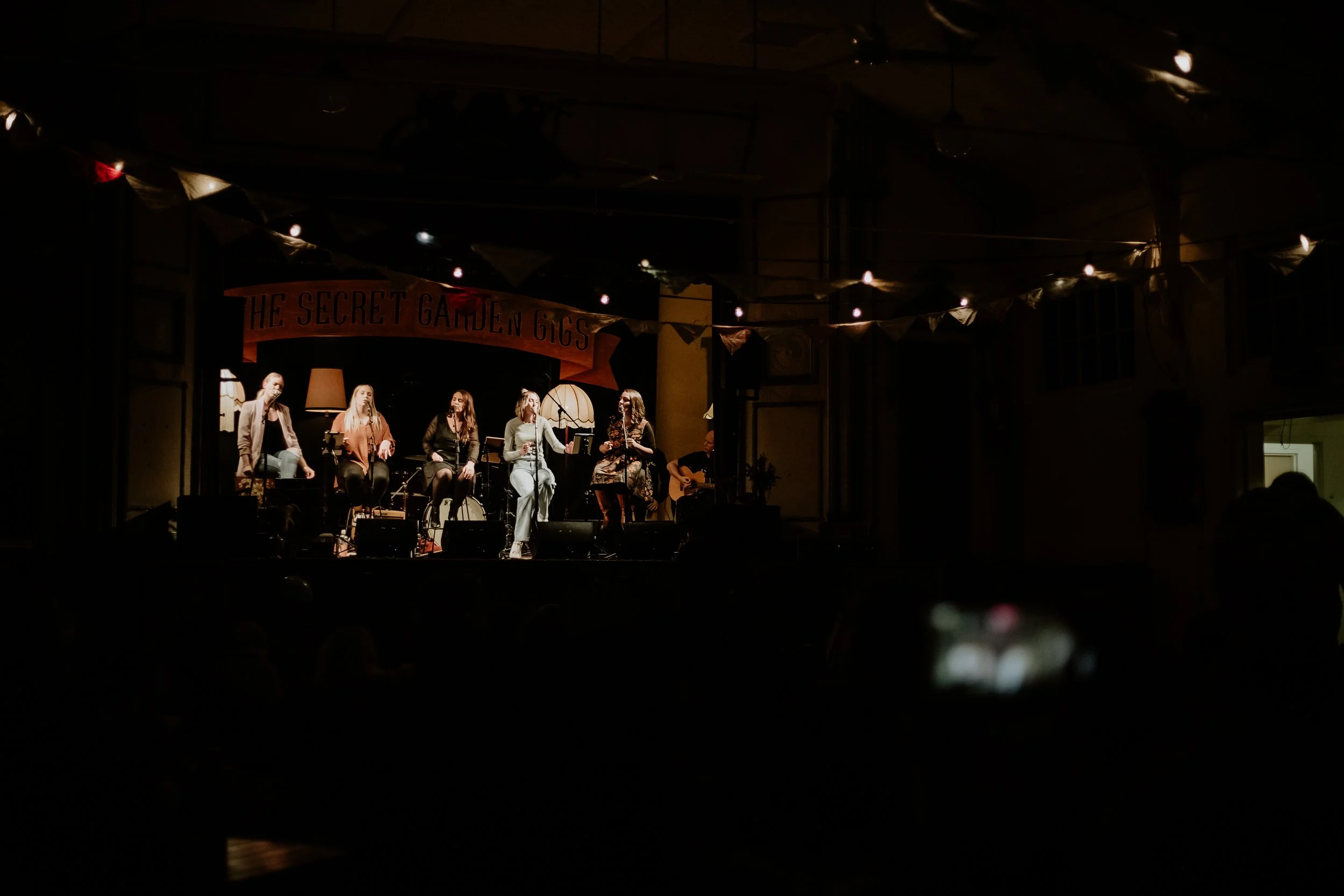 A crowd enjoying The Secret Garden Gigs in a dimly lit hall.