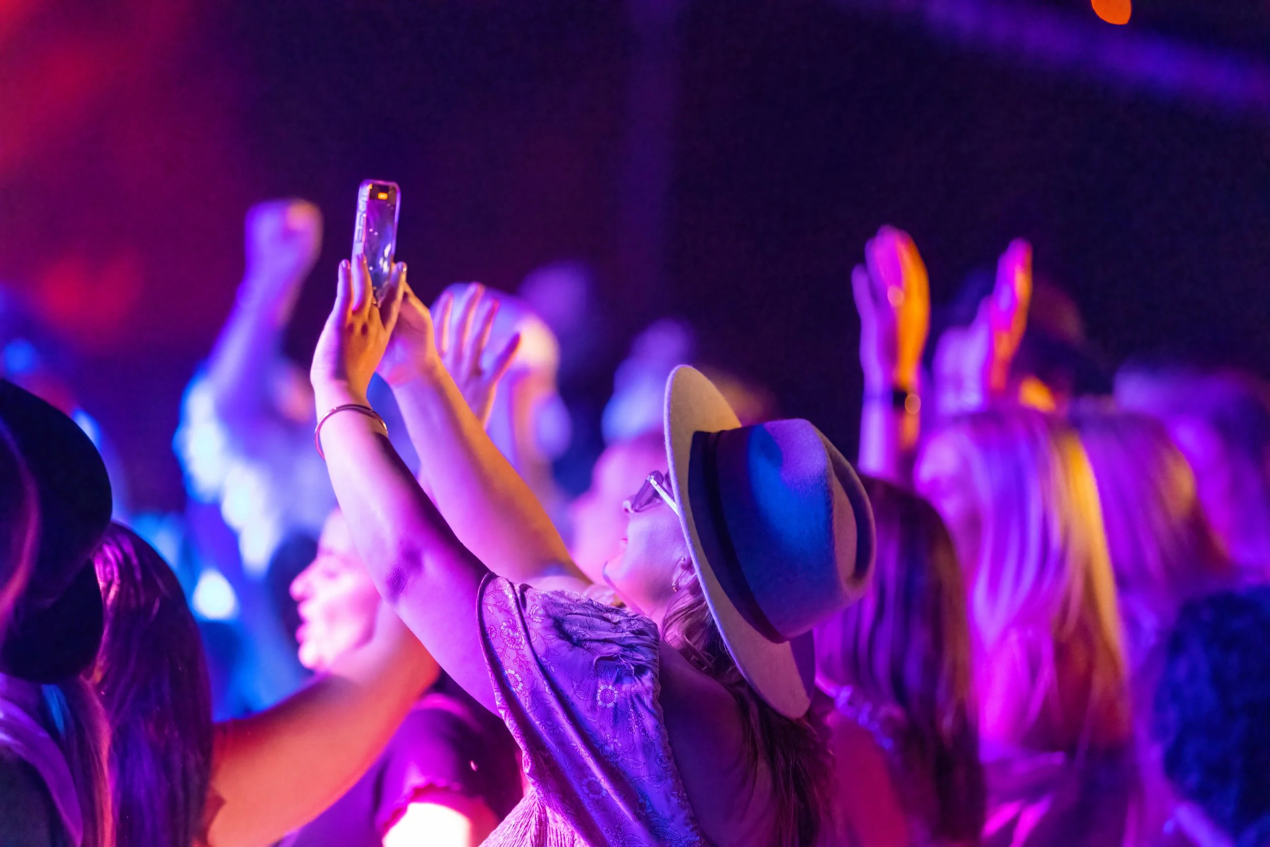 A woman taking a photo of the stage on the dancefloor.