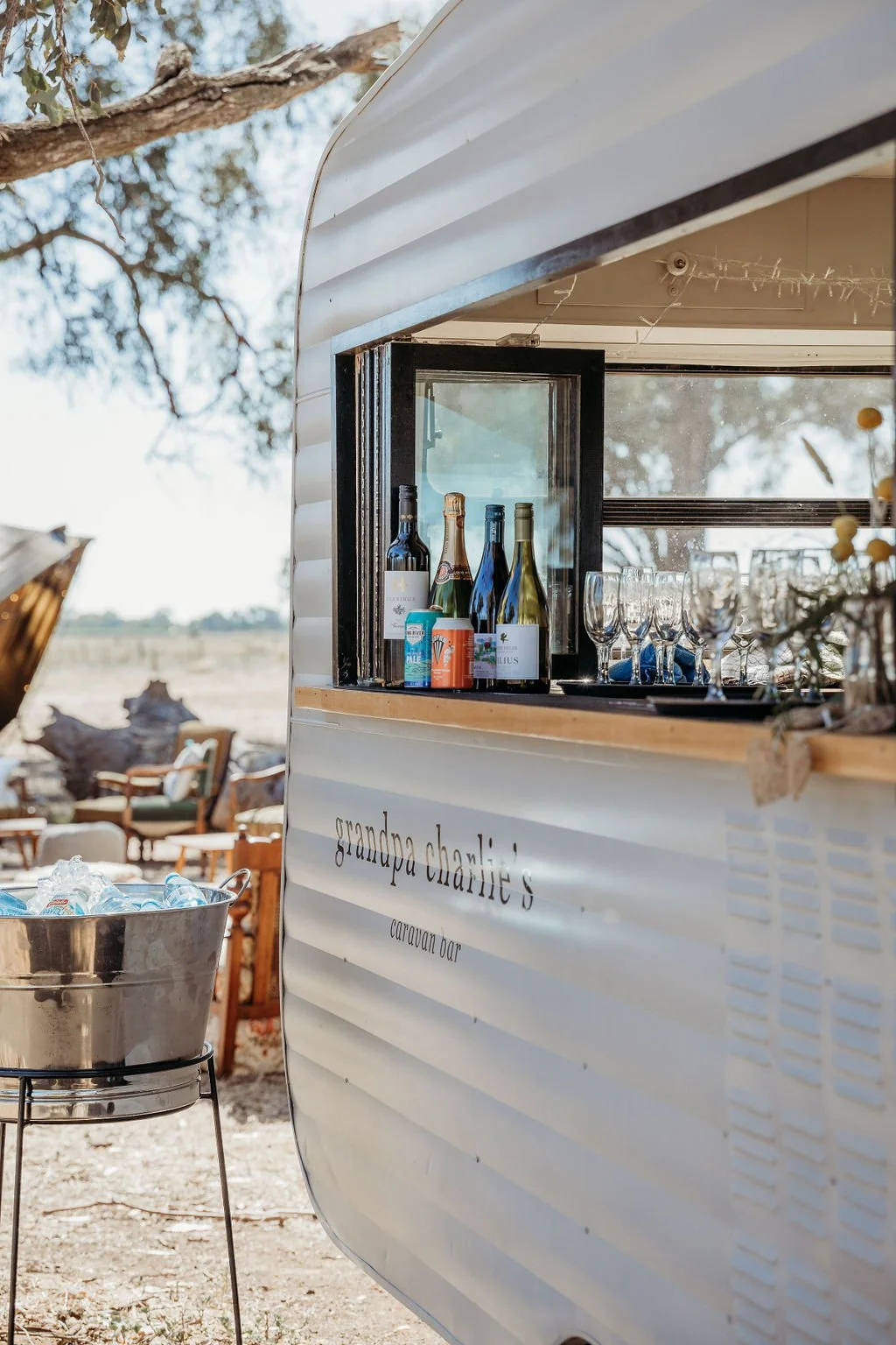 A caravan bar with colorful lights and people enjoying drinks and socializing in an outdoor setting