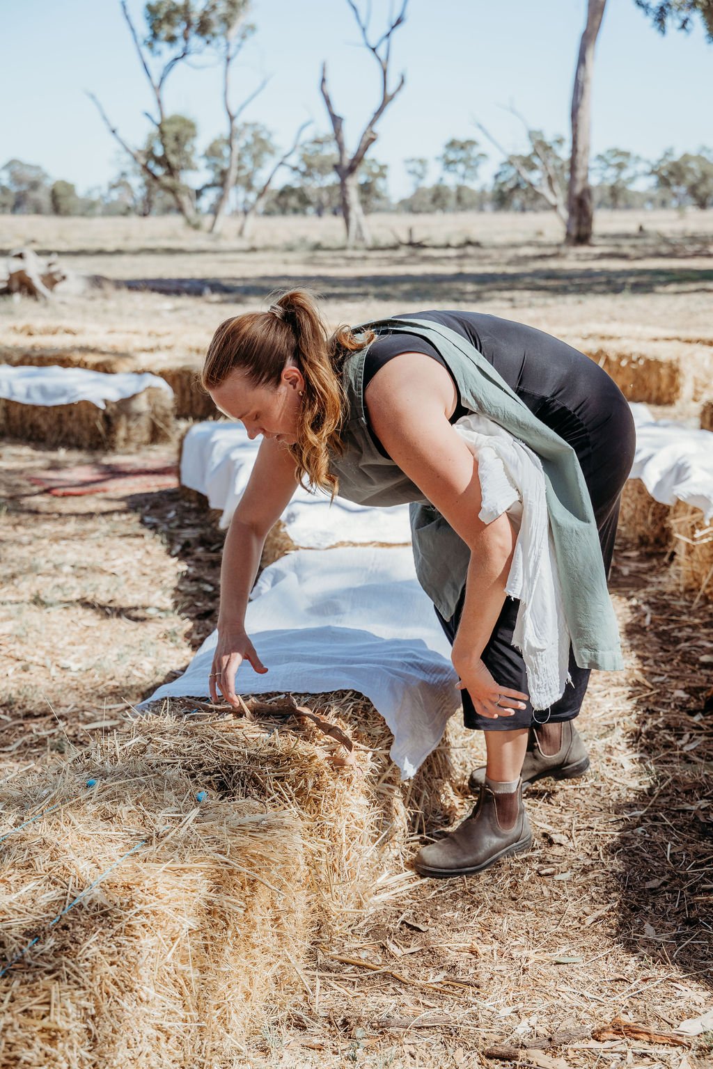 Tenielle setting up hay bails with material for guests to sit on at the ceremony.
