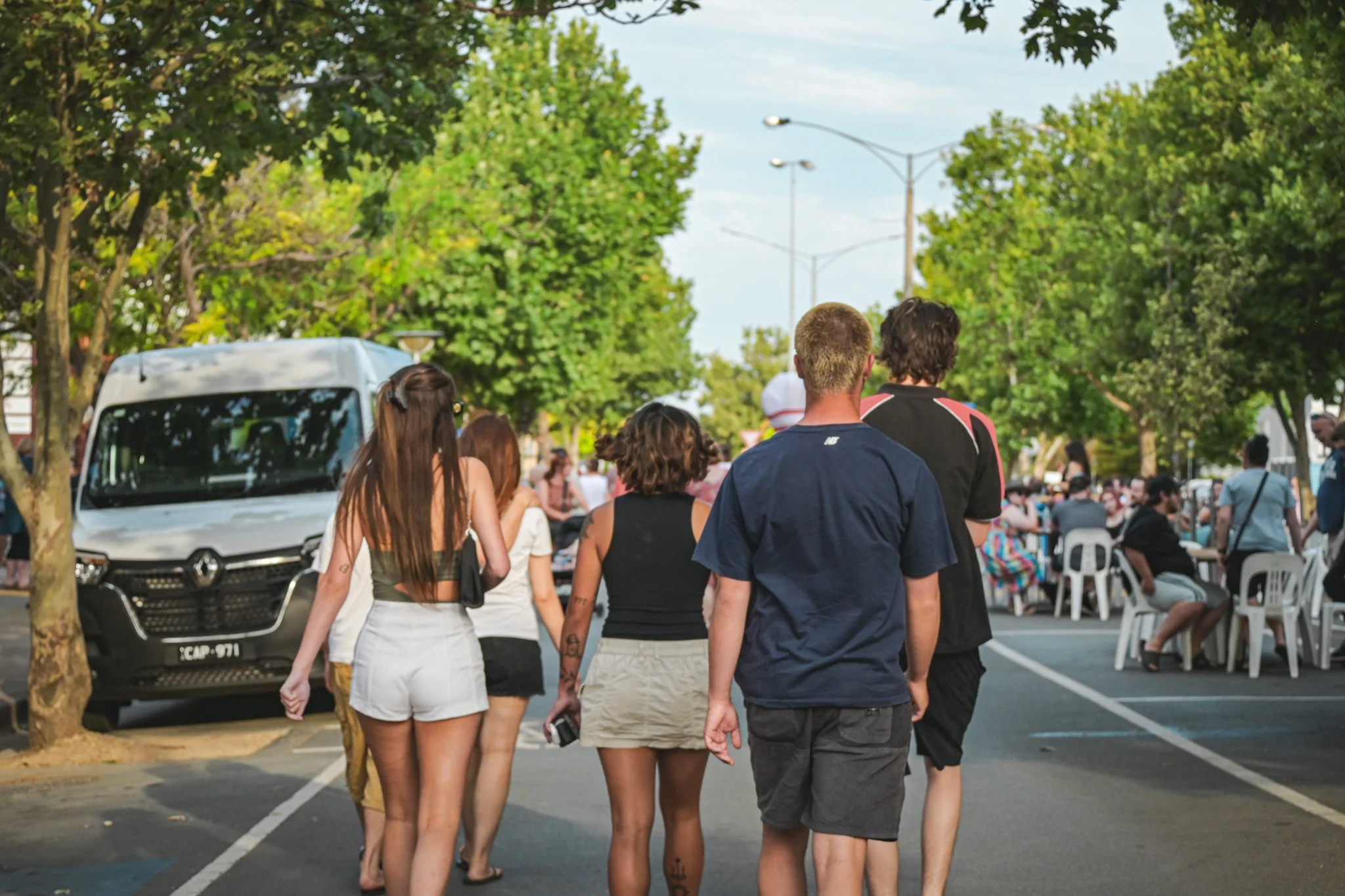 Multicultural crowd walking down a street at a lively food festival.