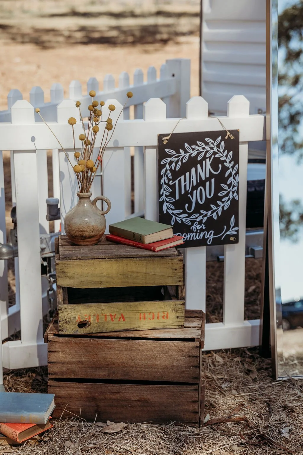 Rustic wedding decor featuring books, flowers, and a "thank you" sign.