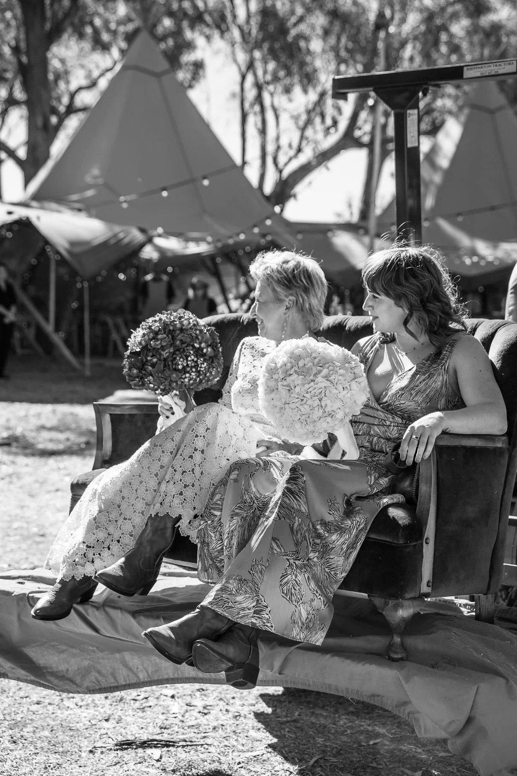 Wedding guests mingling outdoors with spacious tents and greenery in a countryside setting.