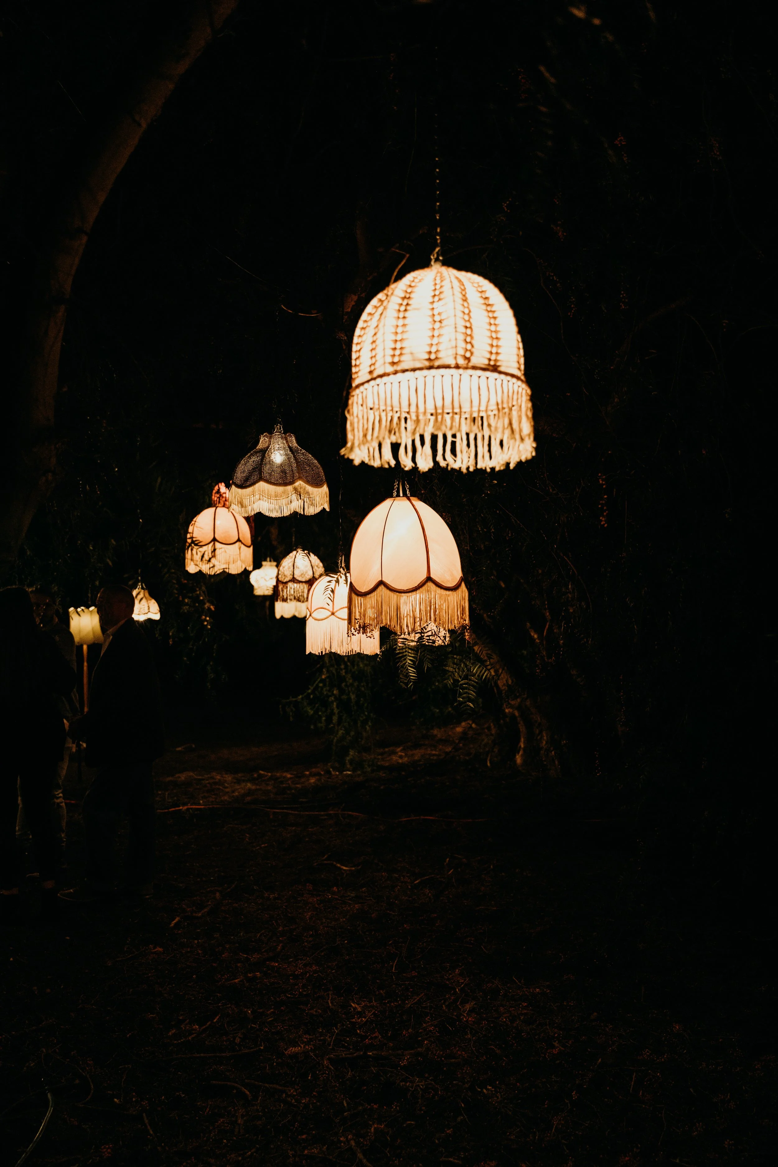Vintage lampshades hang in the dark, appearing to float.