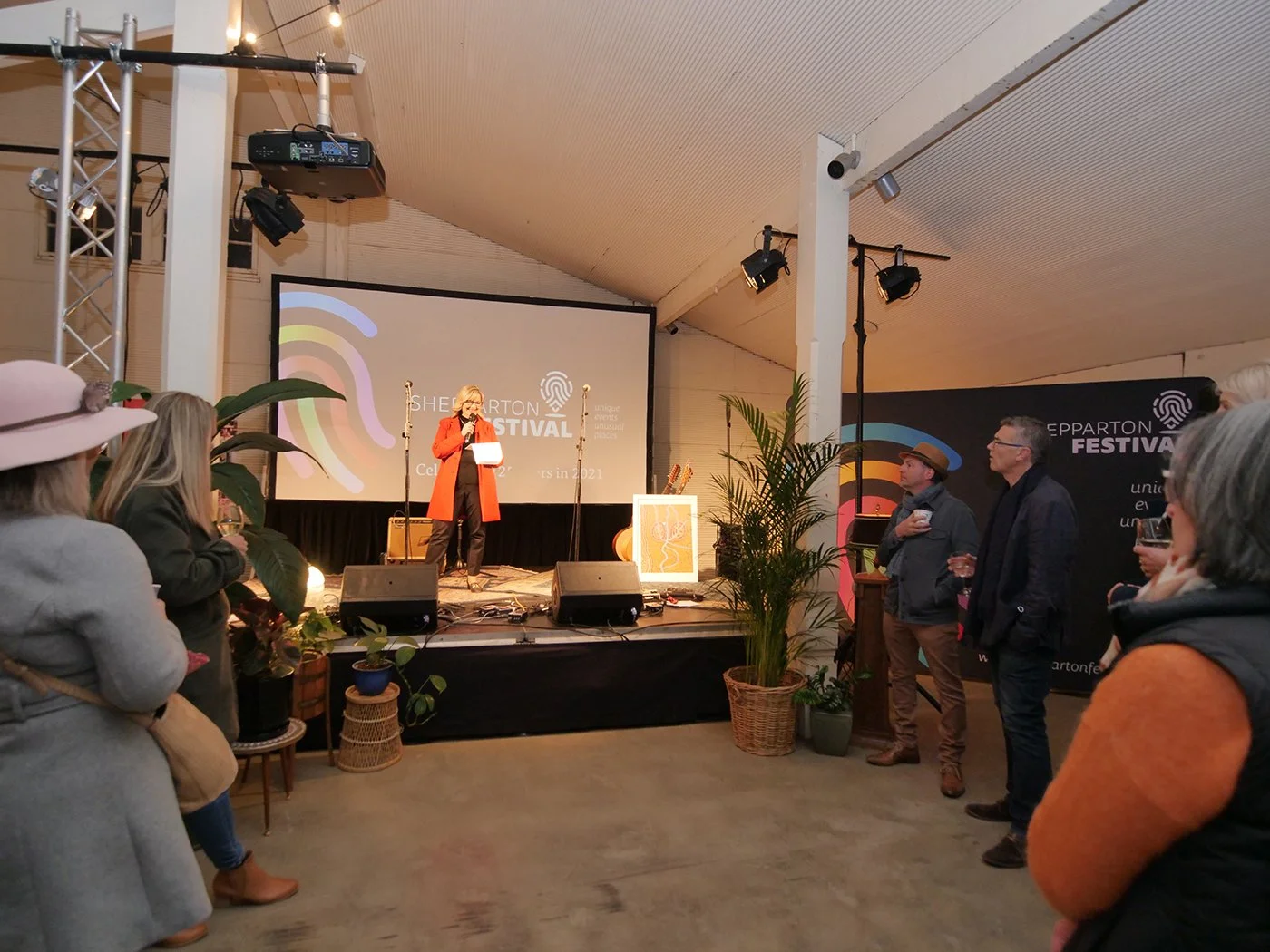 A woman in red giving a speech to the crowd.