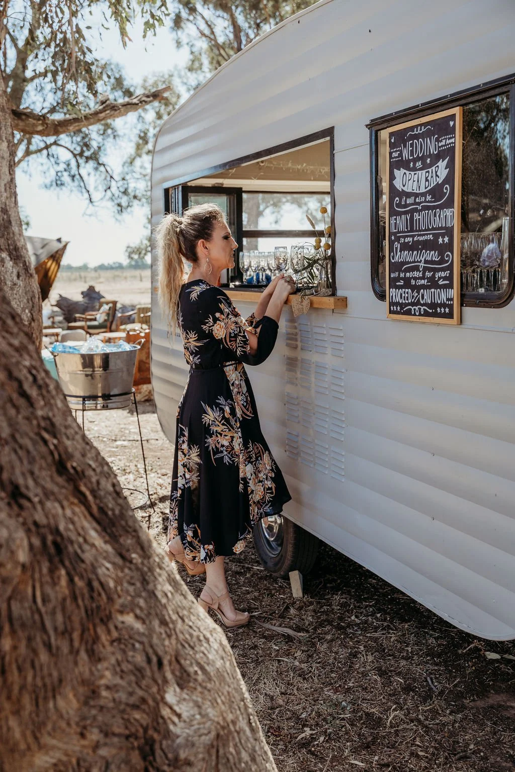 A caravan bar with colorful lights and people enjoying drinks and socializing in an outdoor setting