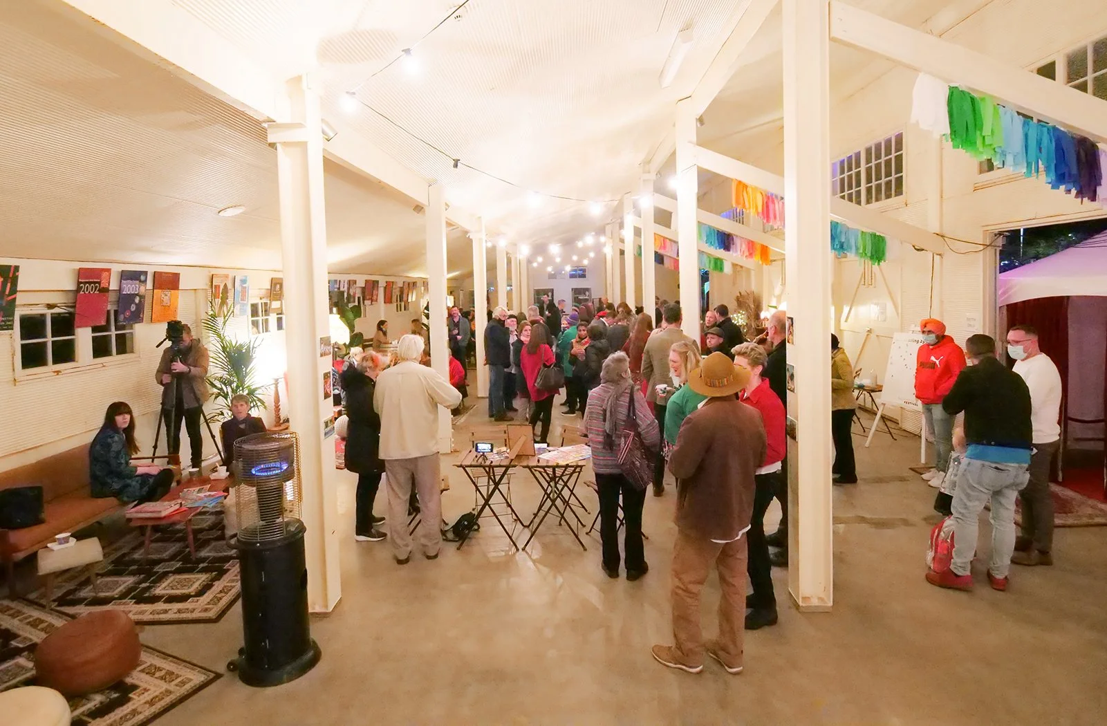 A white event space, filled with people talking and discussing the Shepparton Festival.