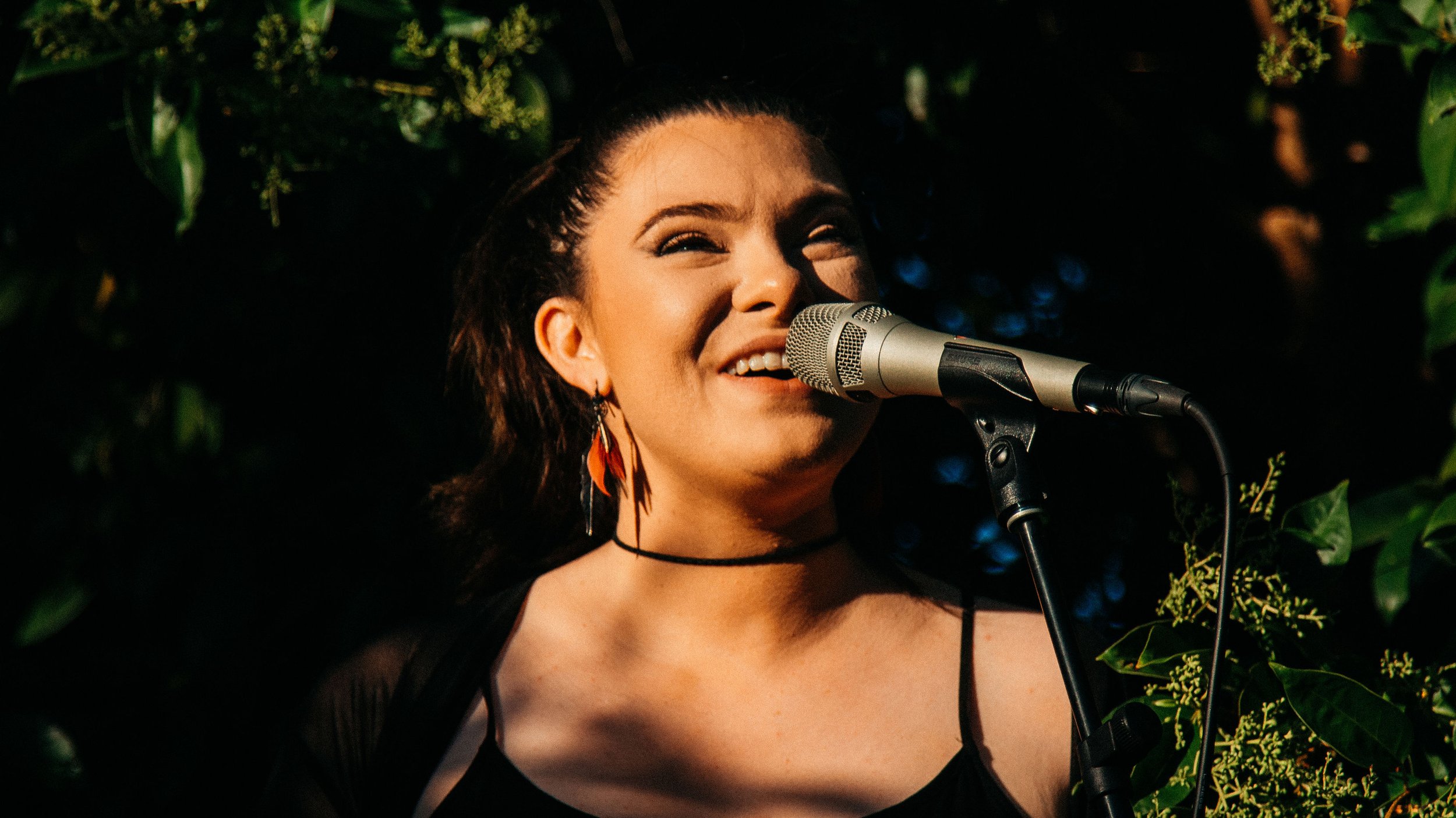 A singer performing at the Secret Garden Gig, captivating the audience amidst lush trees.