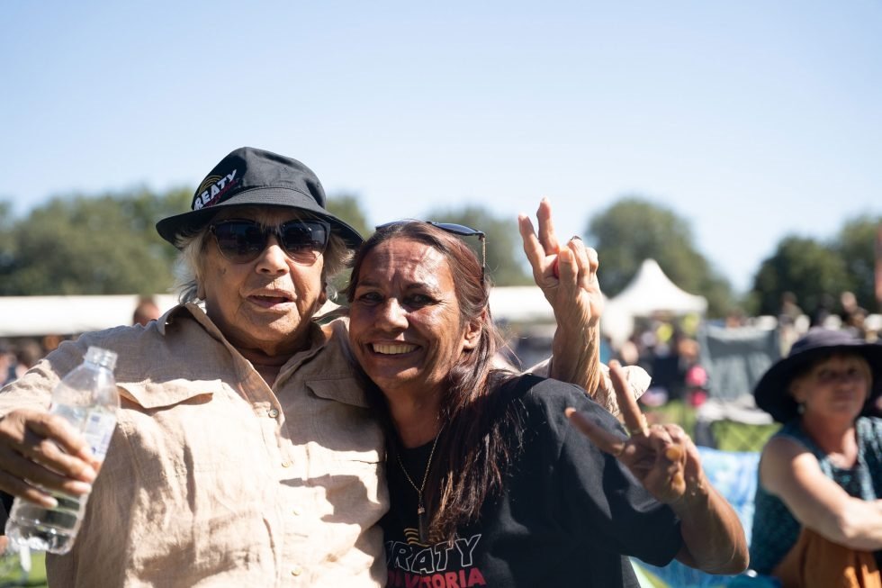 Two individuals smiling and posing for a picture amidst the vibrant atmosphere of a music festival.