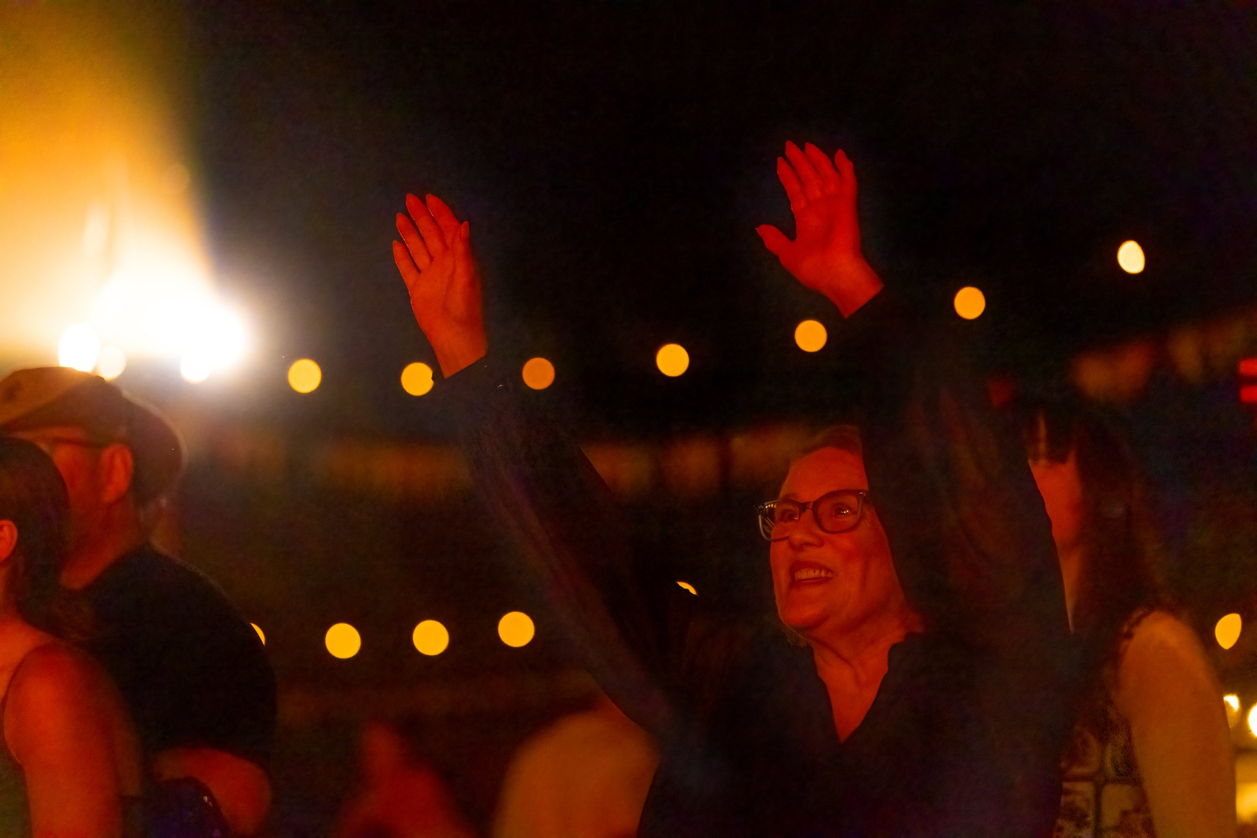 A woman in the crowd, smiling with her hands in the air.