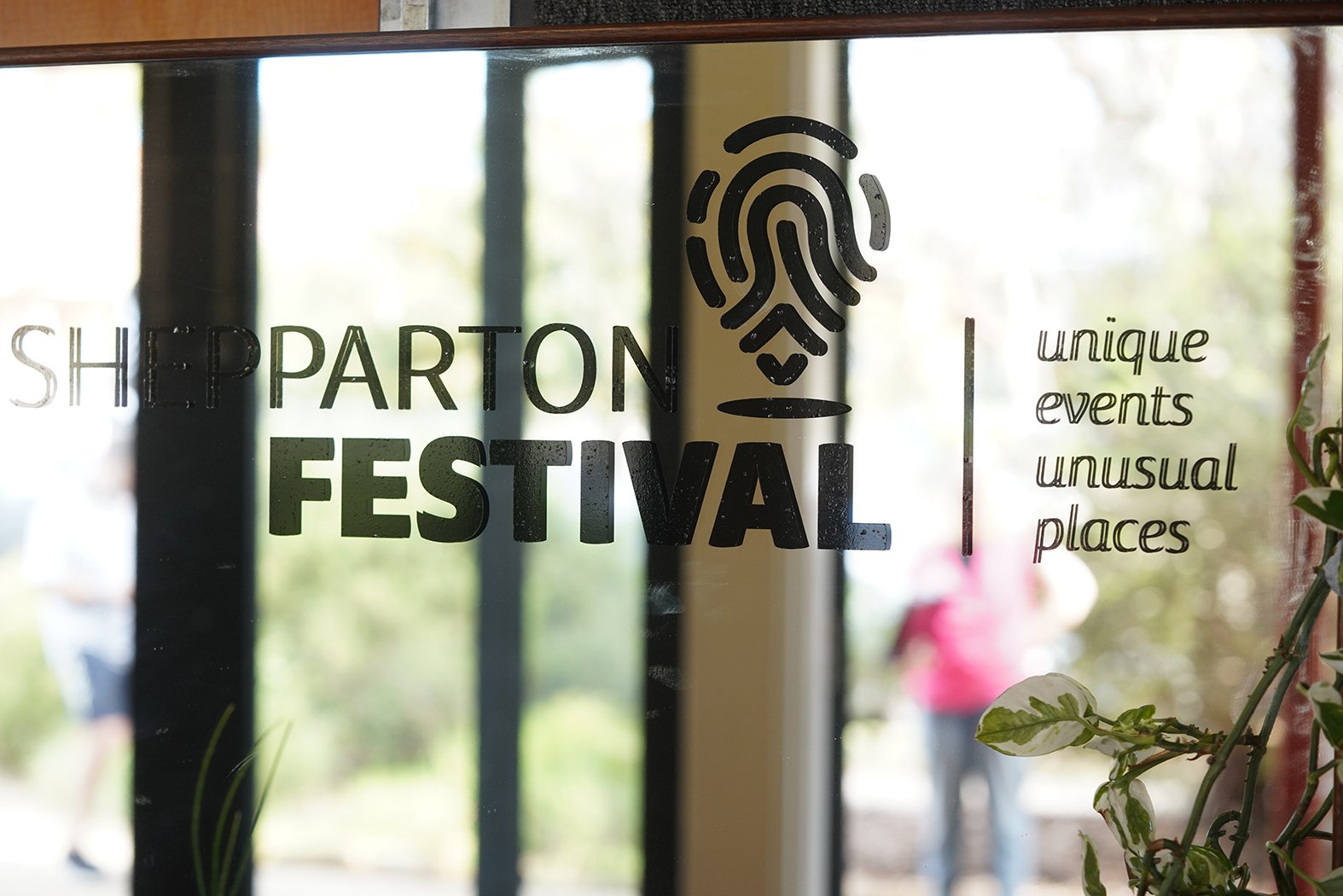 A mirrored sign with the Shepparton Festival logo on it. It says "unique events unusual places".