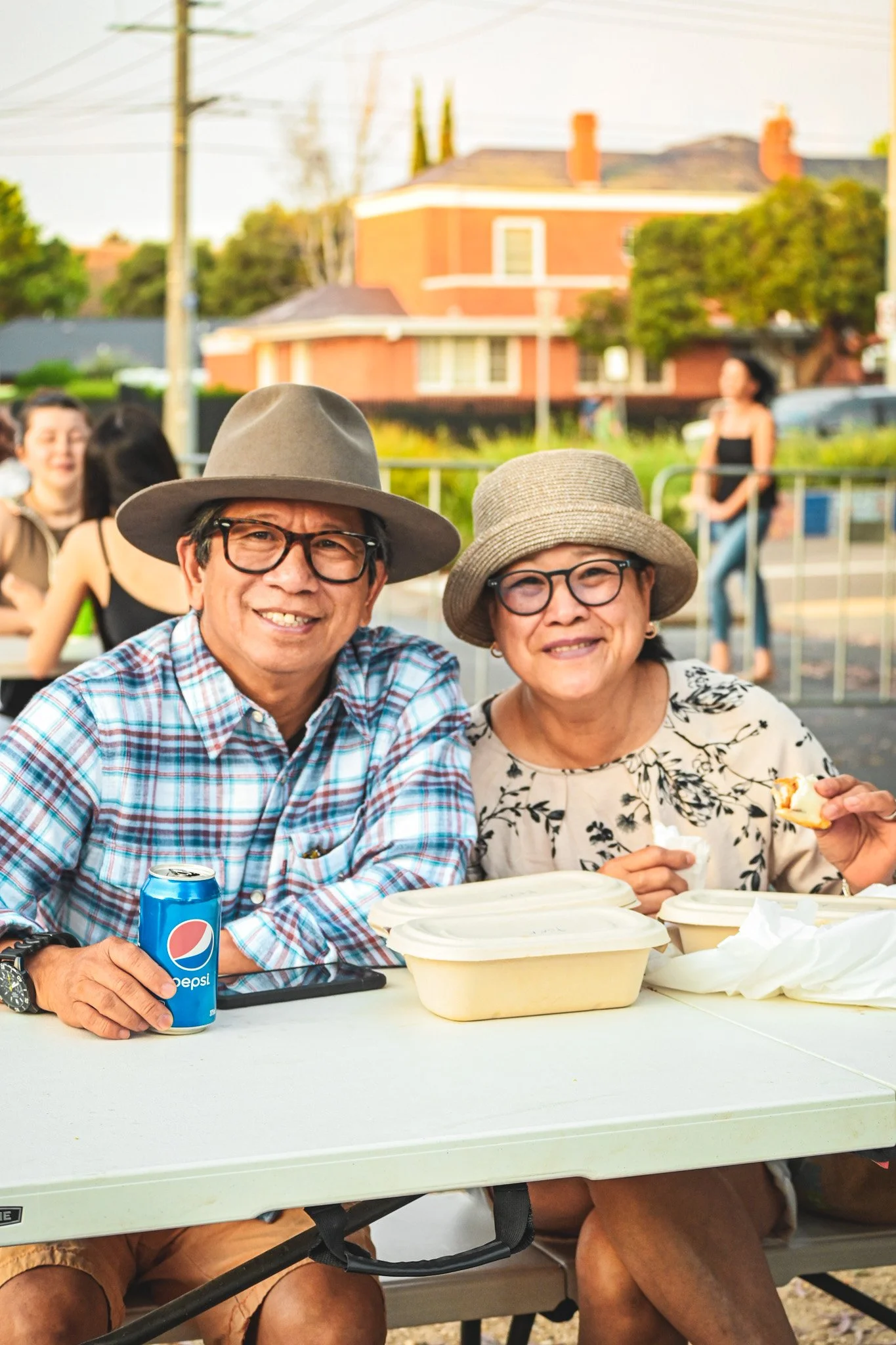 An image of a man and woman sitting at a table, immersed in the vibrant atmosphere of a food festival.