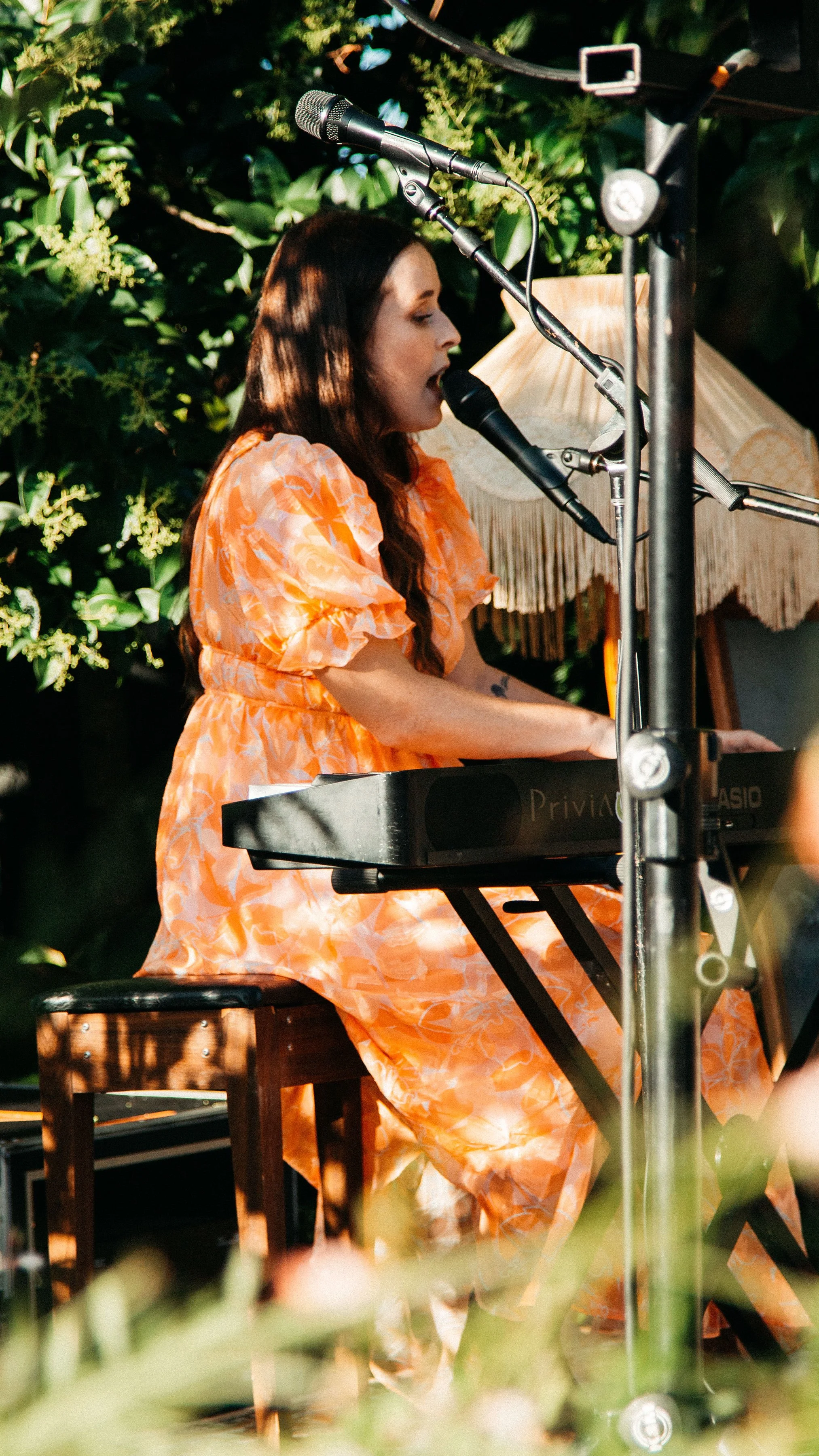 Musician in orange dress playing keyboard at Secret Garden Gig.