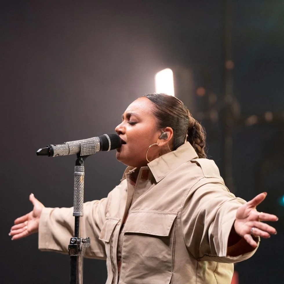 Jessica Mauboy in a jacket passionately singing into a microphone during the 'Treaty Day Out' event.