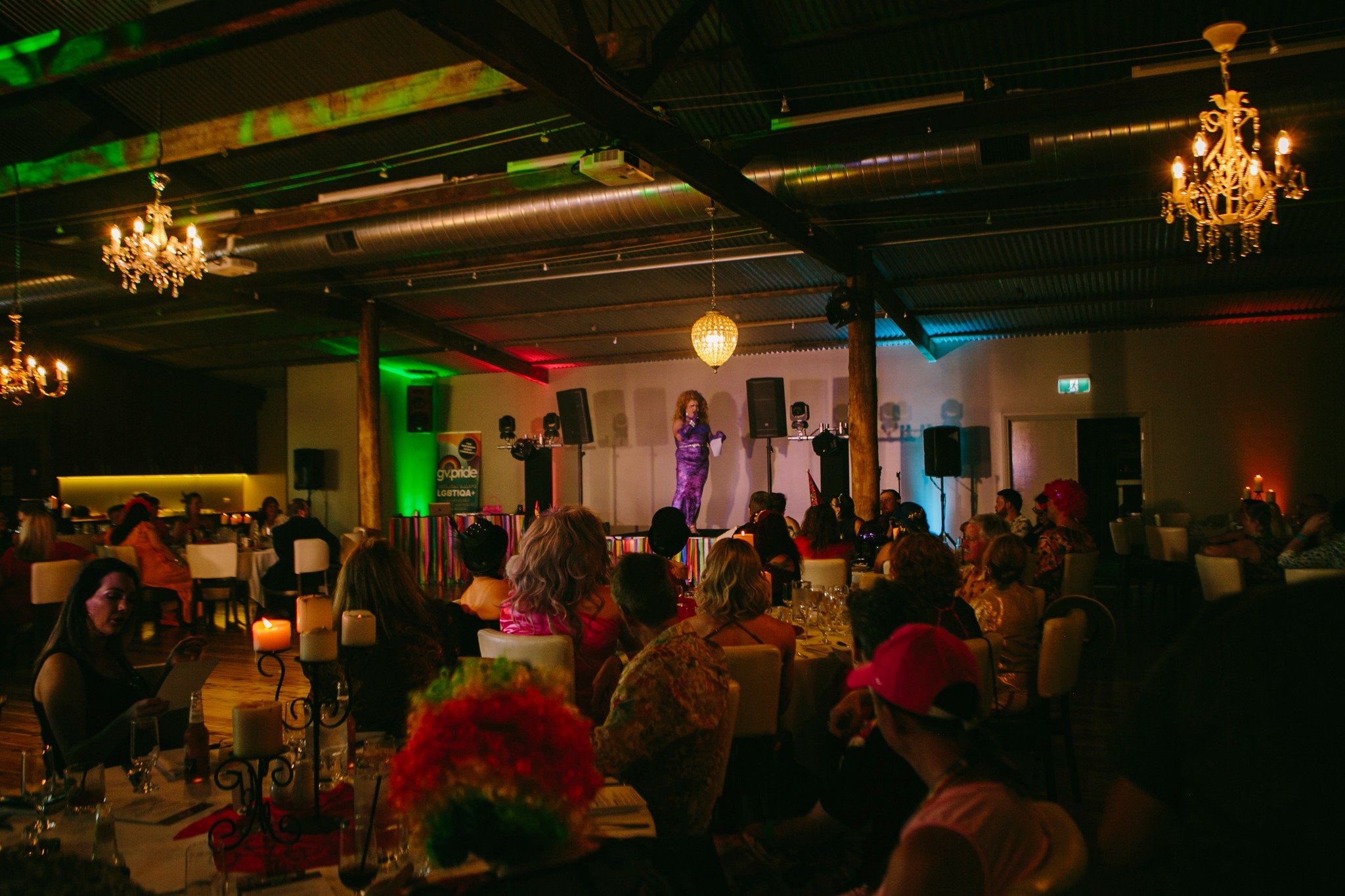 People gathered around tables in a large room for Pride Ball event.