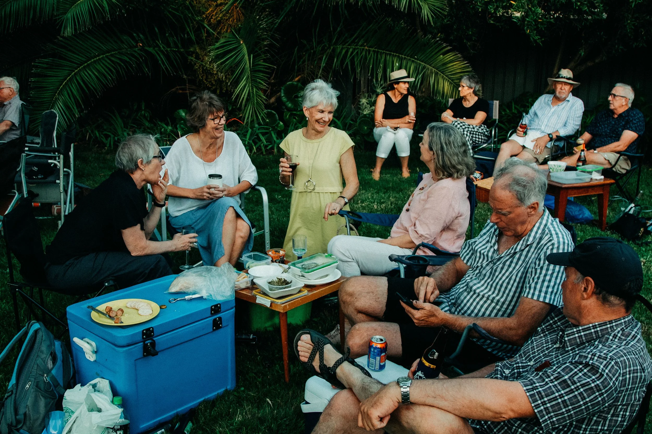 A group of people sitting around a table in the grass at the Secret Garden Gig.