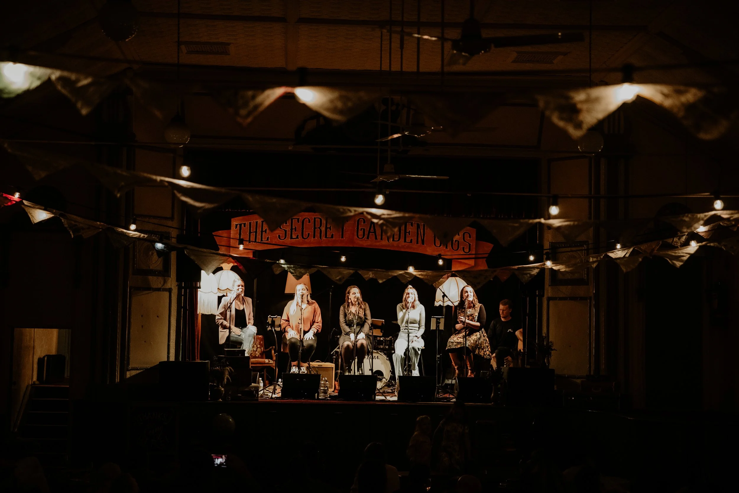 Five women seated, performing for the crowd.