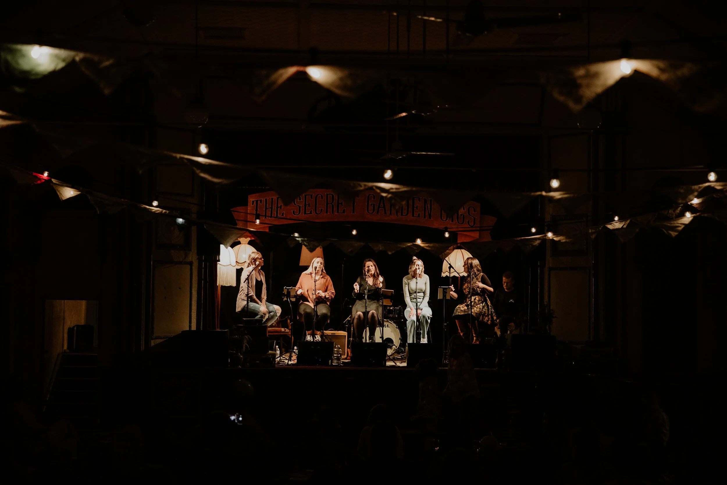 Women singing harmoniously for an eraptured audience.