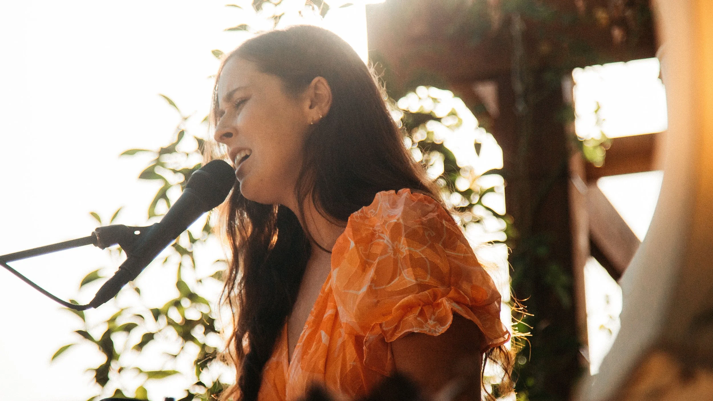 Female singer serenading into a microphone at Secret Garden Gig