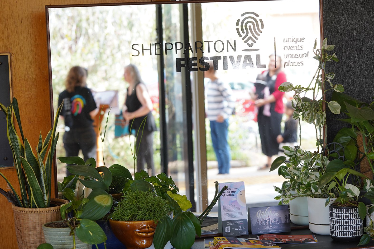A mirror reflecting people enjoying the Shepparton Festival Guide Launch.