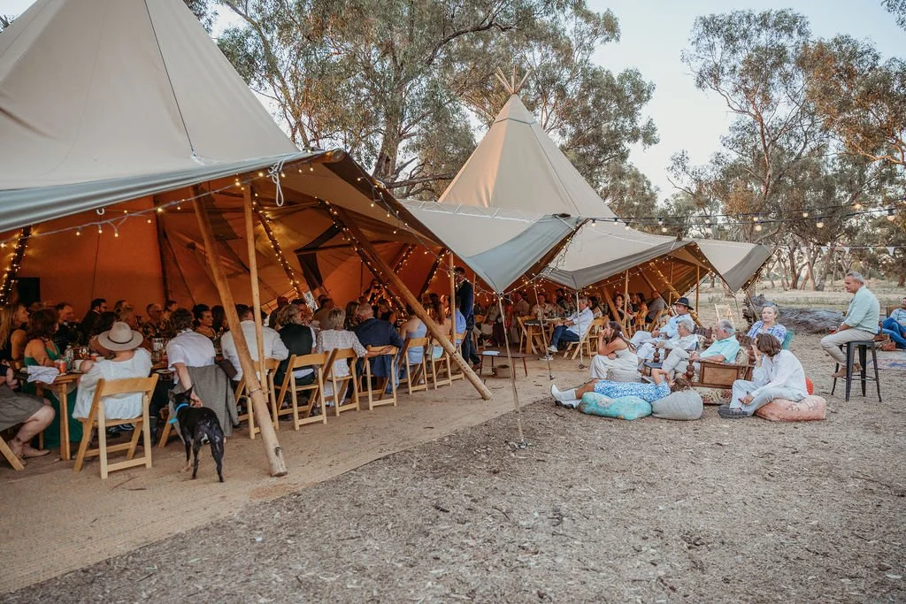 Long tables set up under tents for wedding guests to dine and celebrate.