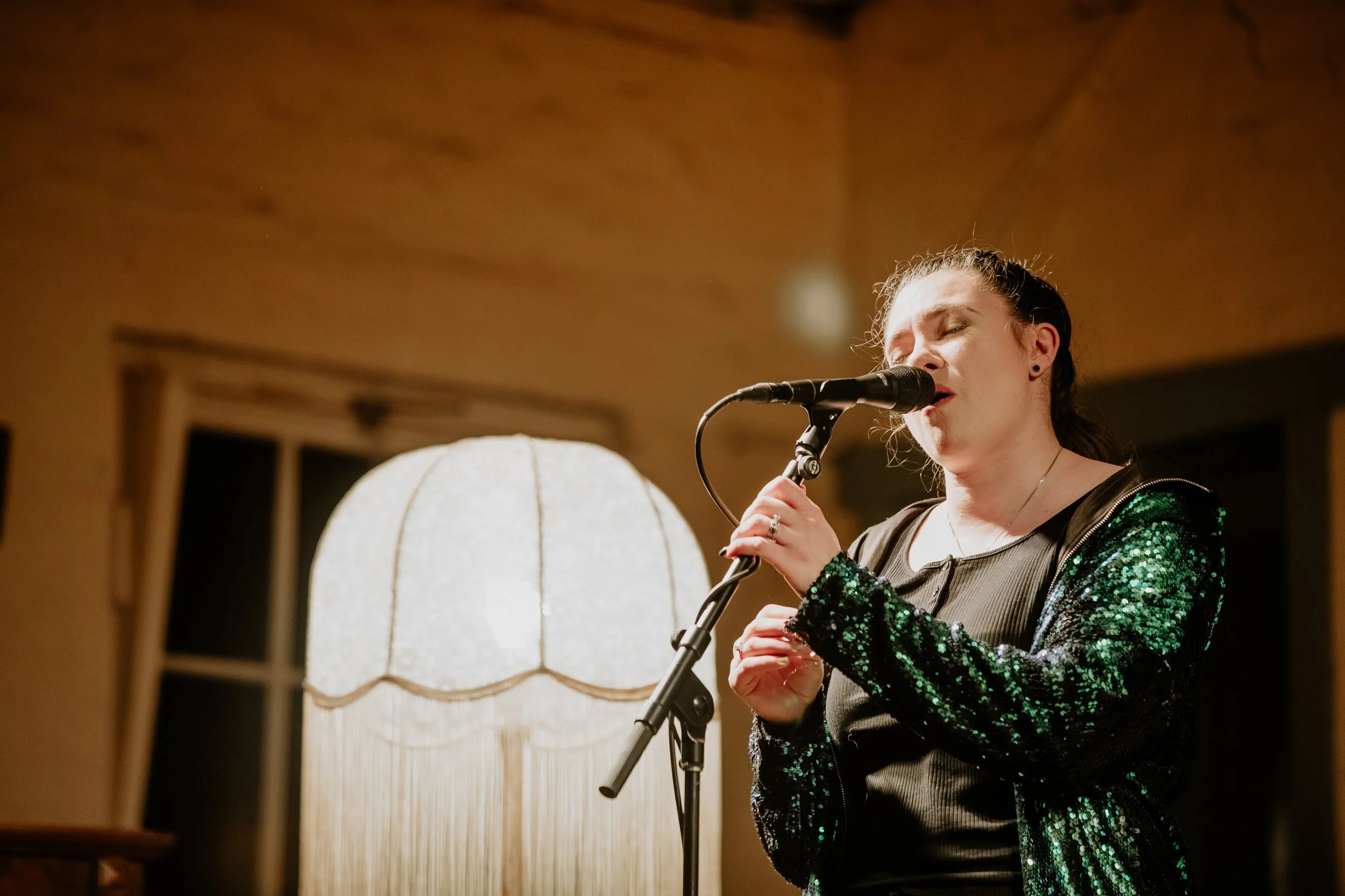 A woman singing in a sparkly jacket.