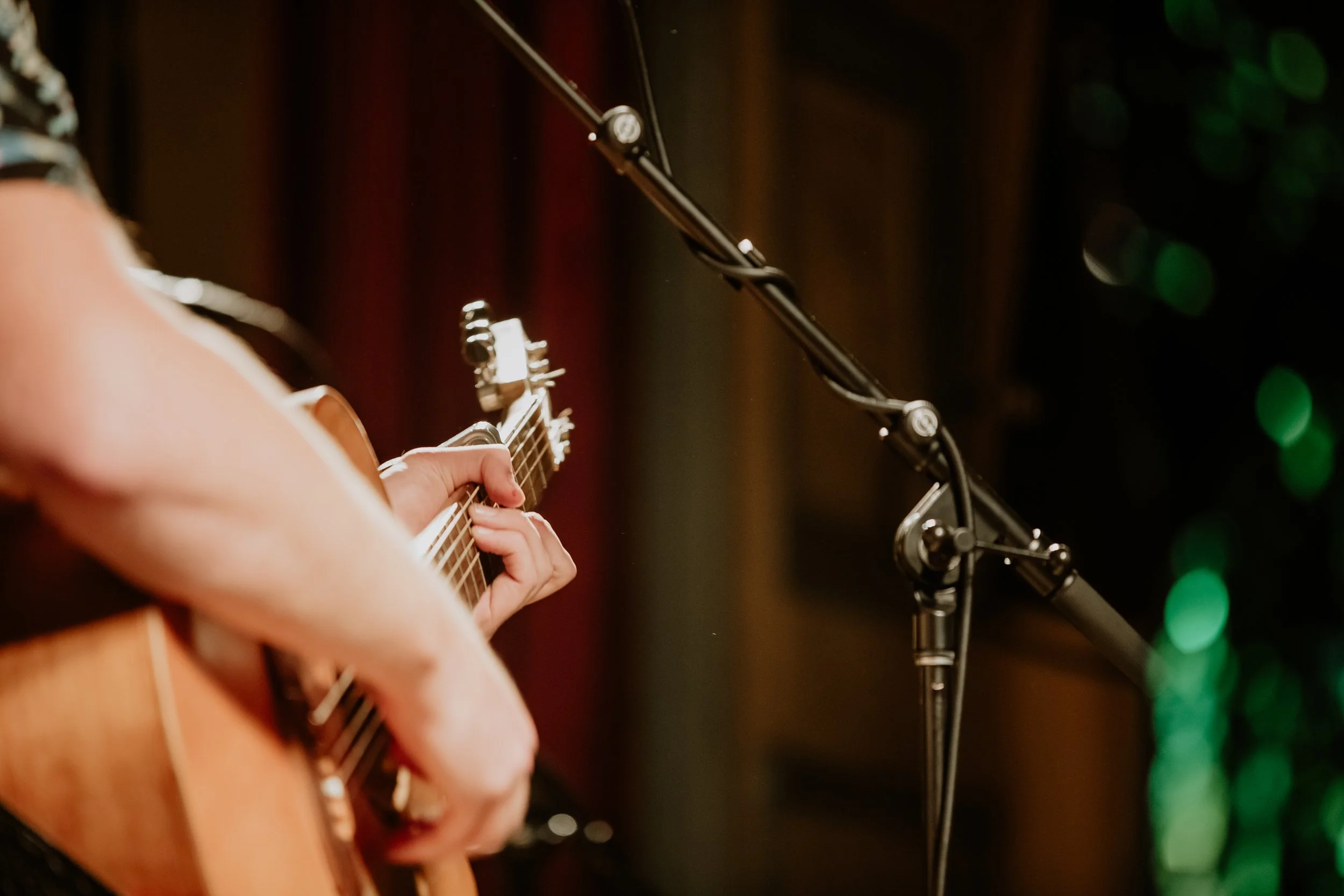 A close up of an acoustic guitar and mic stand.