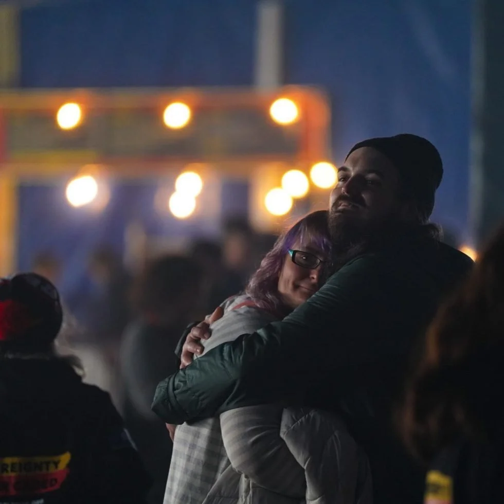 A couple joyfully embraces at the Treaty Day Out event, expressing their love and happiness.