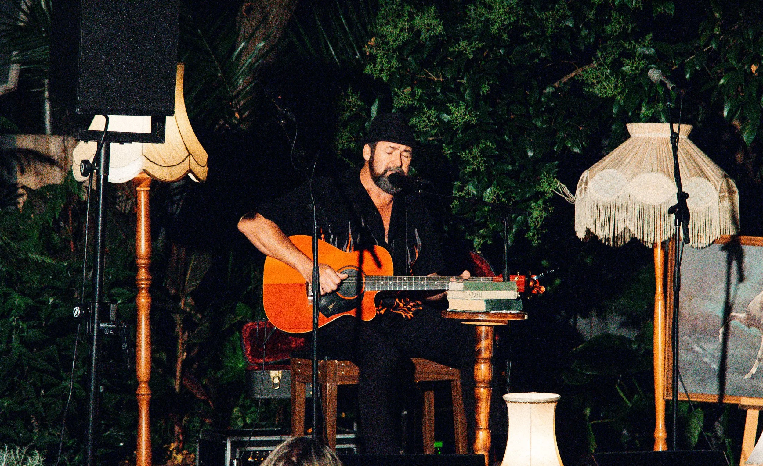 A musician strums an acoustic guitar, captivating a crowd with his melodic tunes.