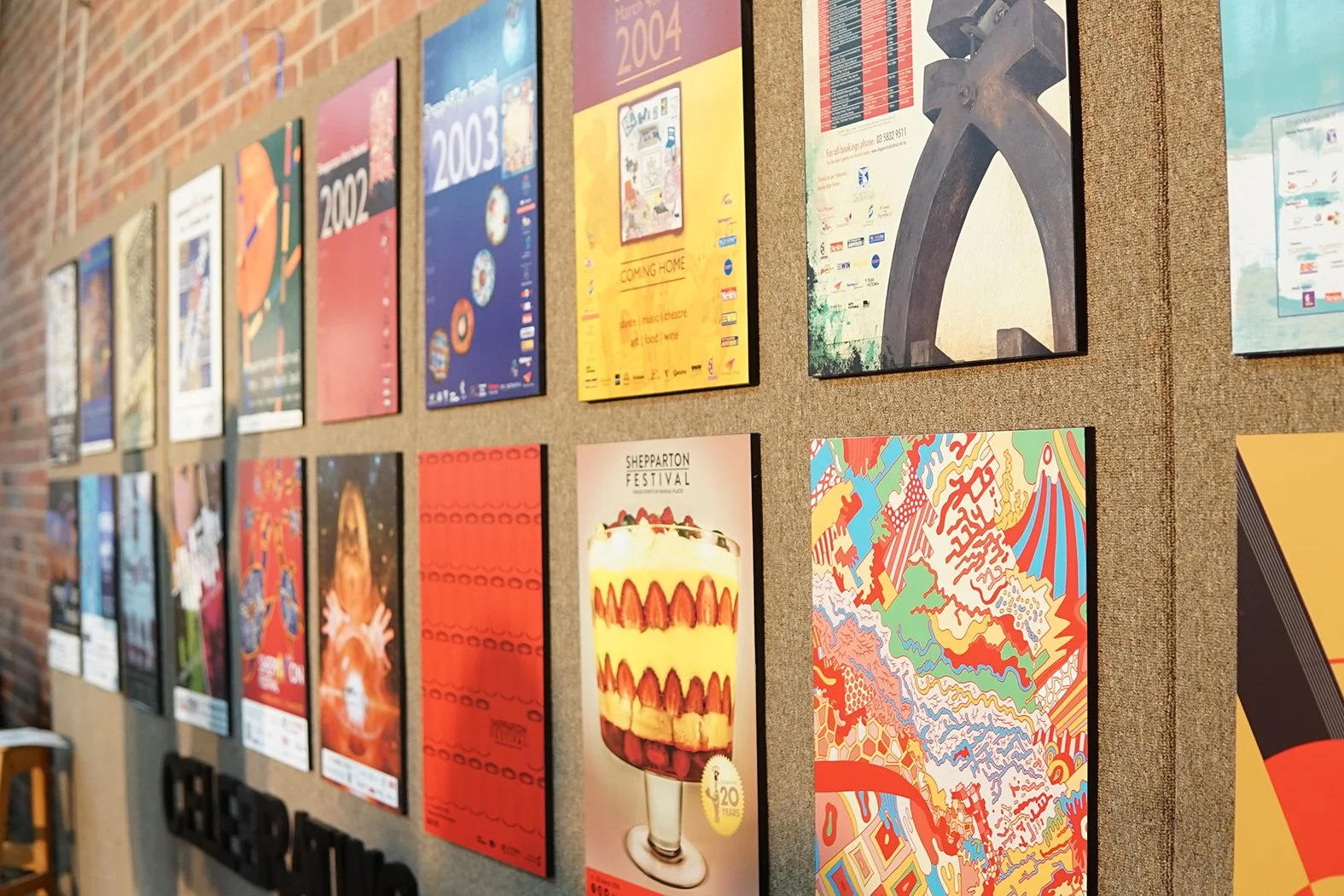 A gallery of bright colourful artworks on a brick wall.