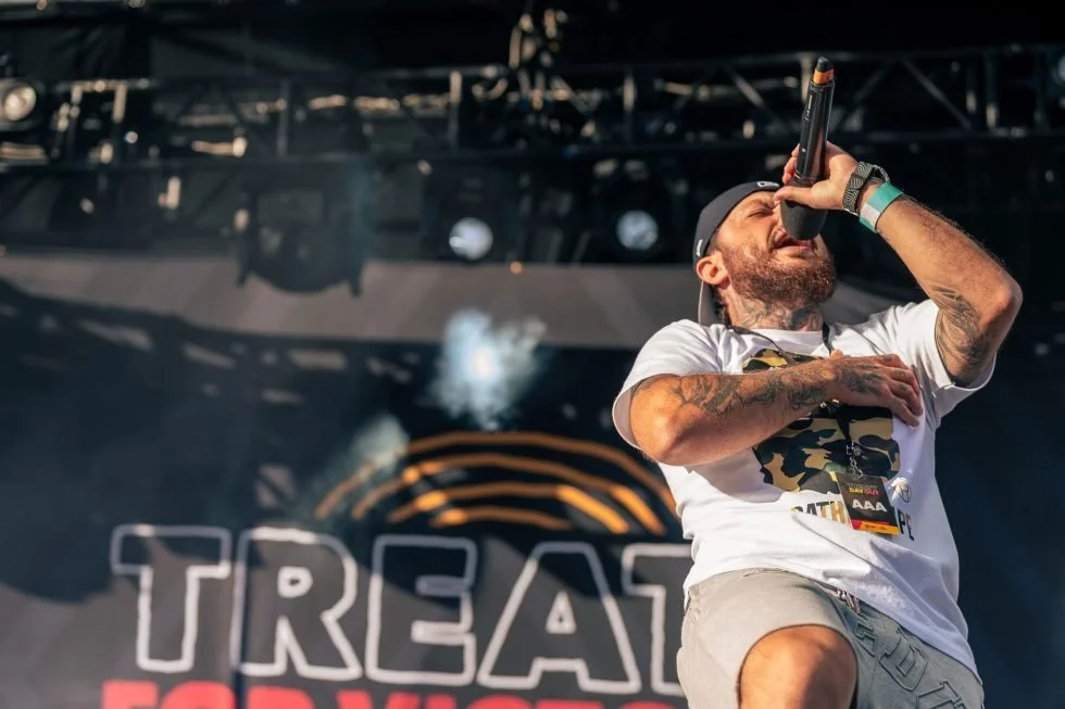 A man on stage with his hands raised in the air during 'Treaty Day Out'.