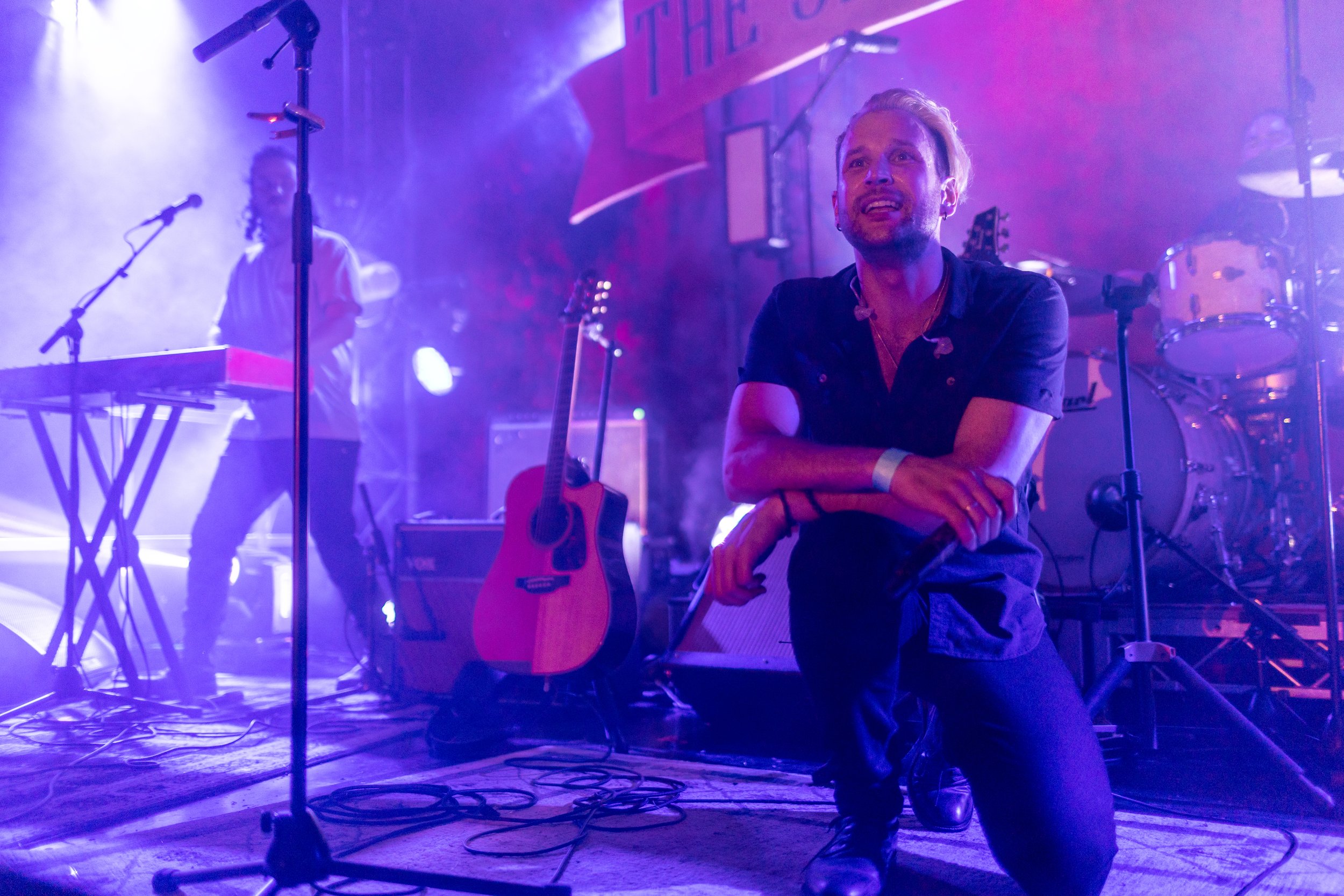 A man takes a knee while performing on stage.