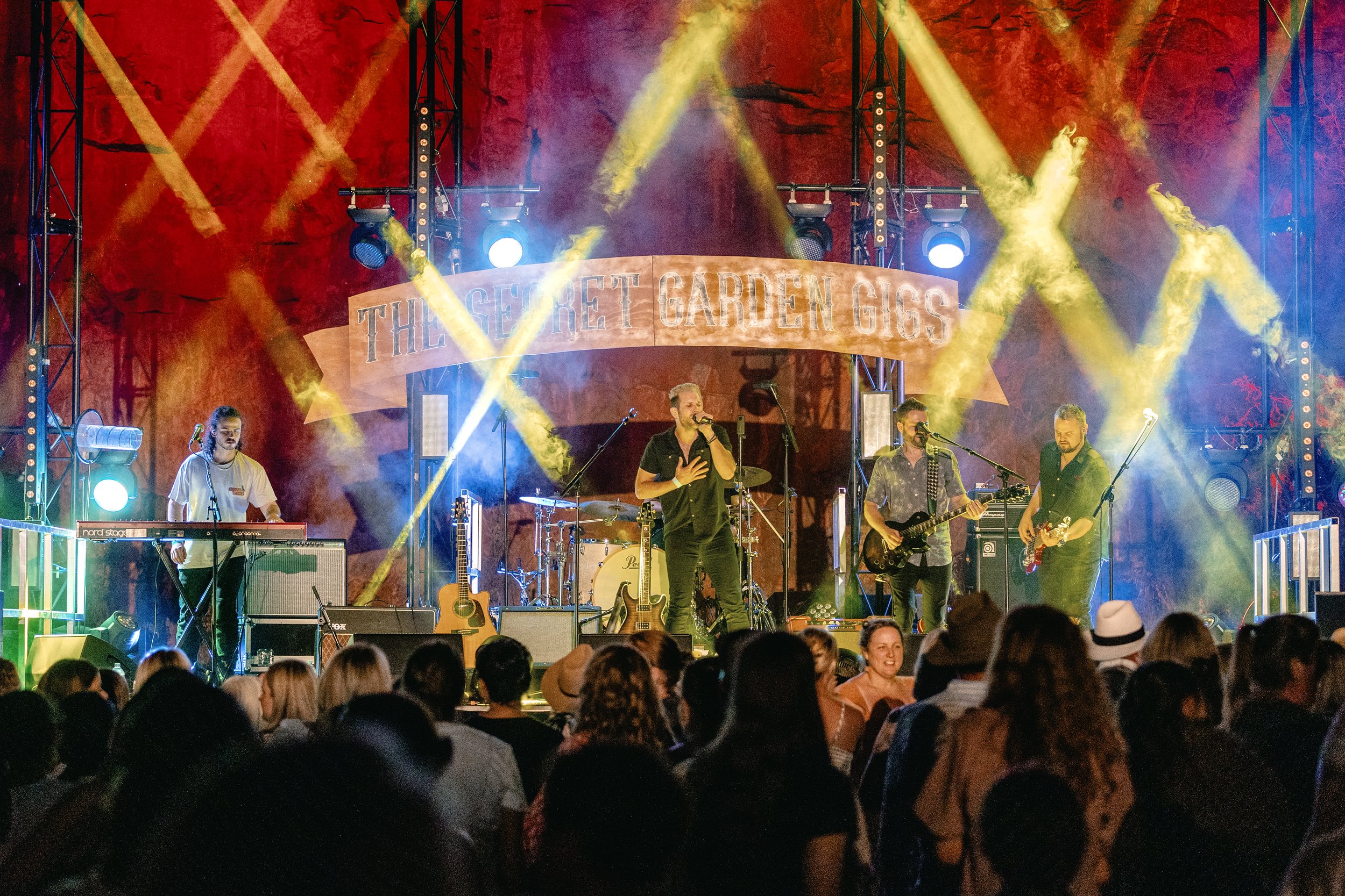 A band performing with criss-crossing lights.